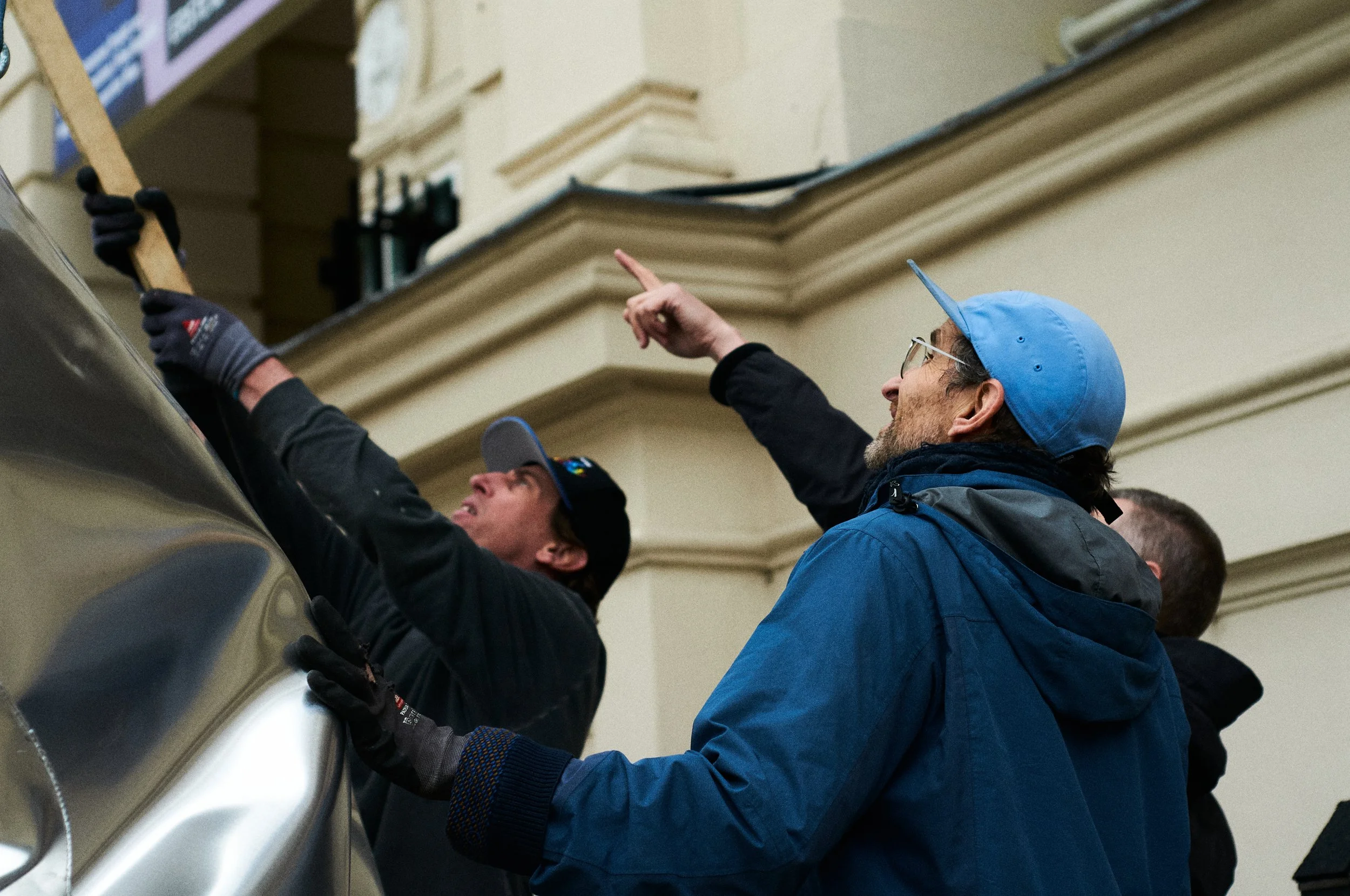 People working on a project or installation indoors, with one person pointing and others focusing.