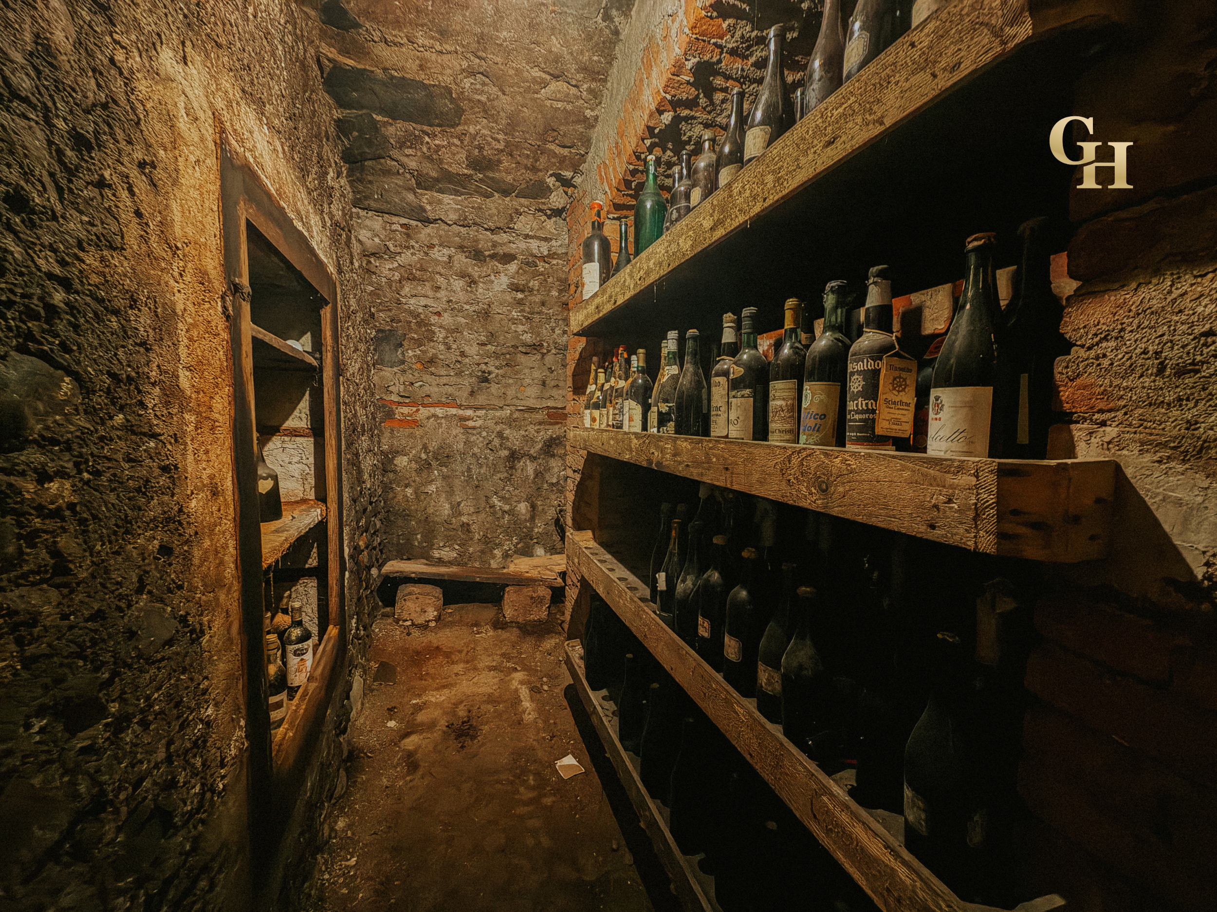 A brick wine cellar with shelves holding limited wine bottles in wooden racks.
