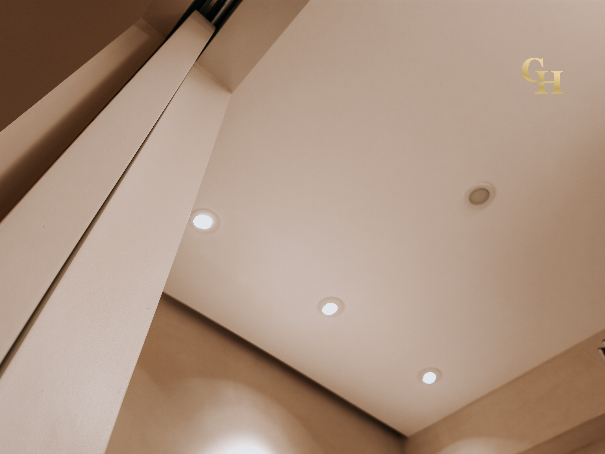 Ceiling with recessed lighting and a ventilation grill in a modern interior.