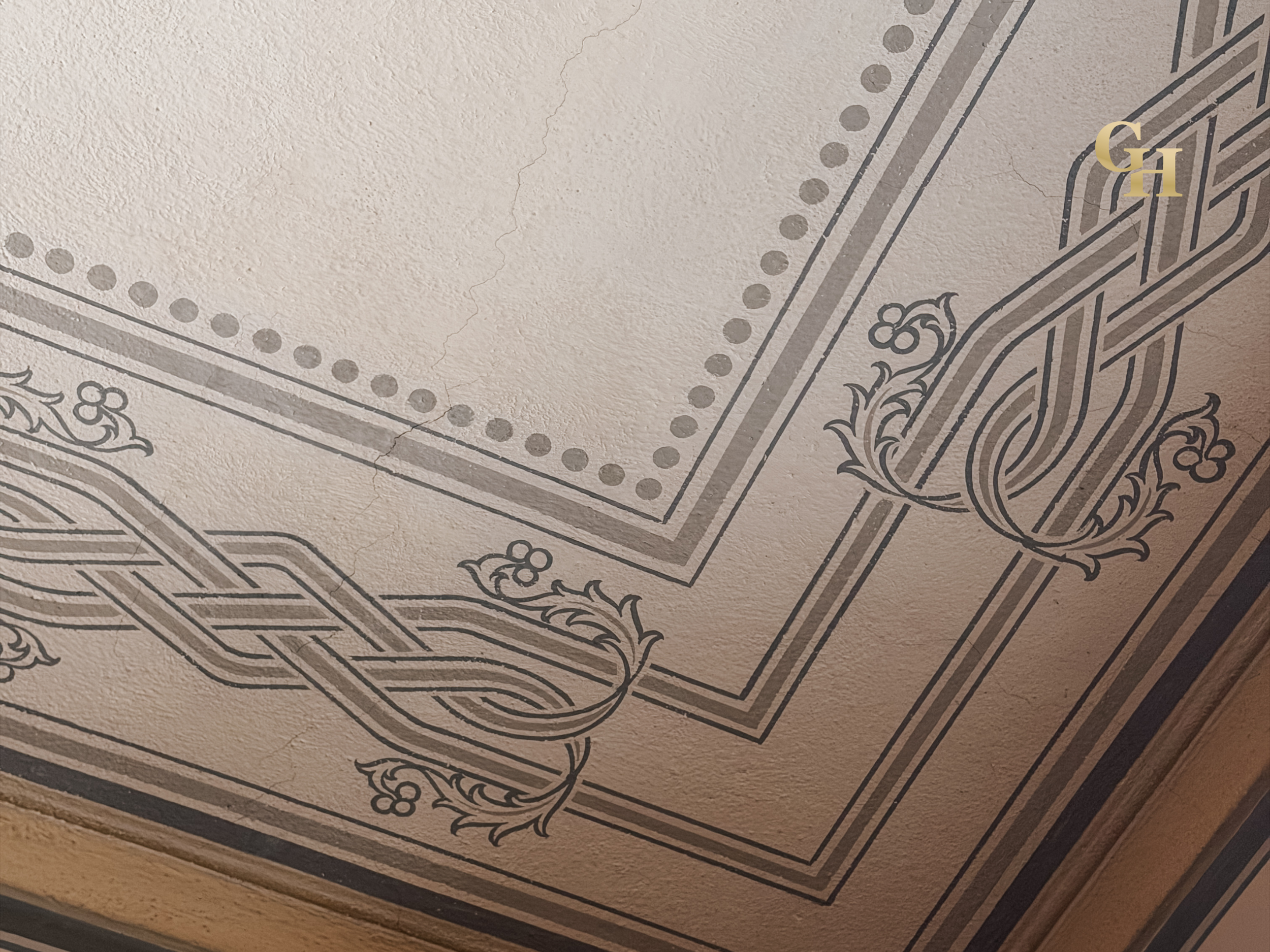 Close-up of a section of a vintage paper bill with detailed black and gray ornate designs and the letter G and H printed in gold.