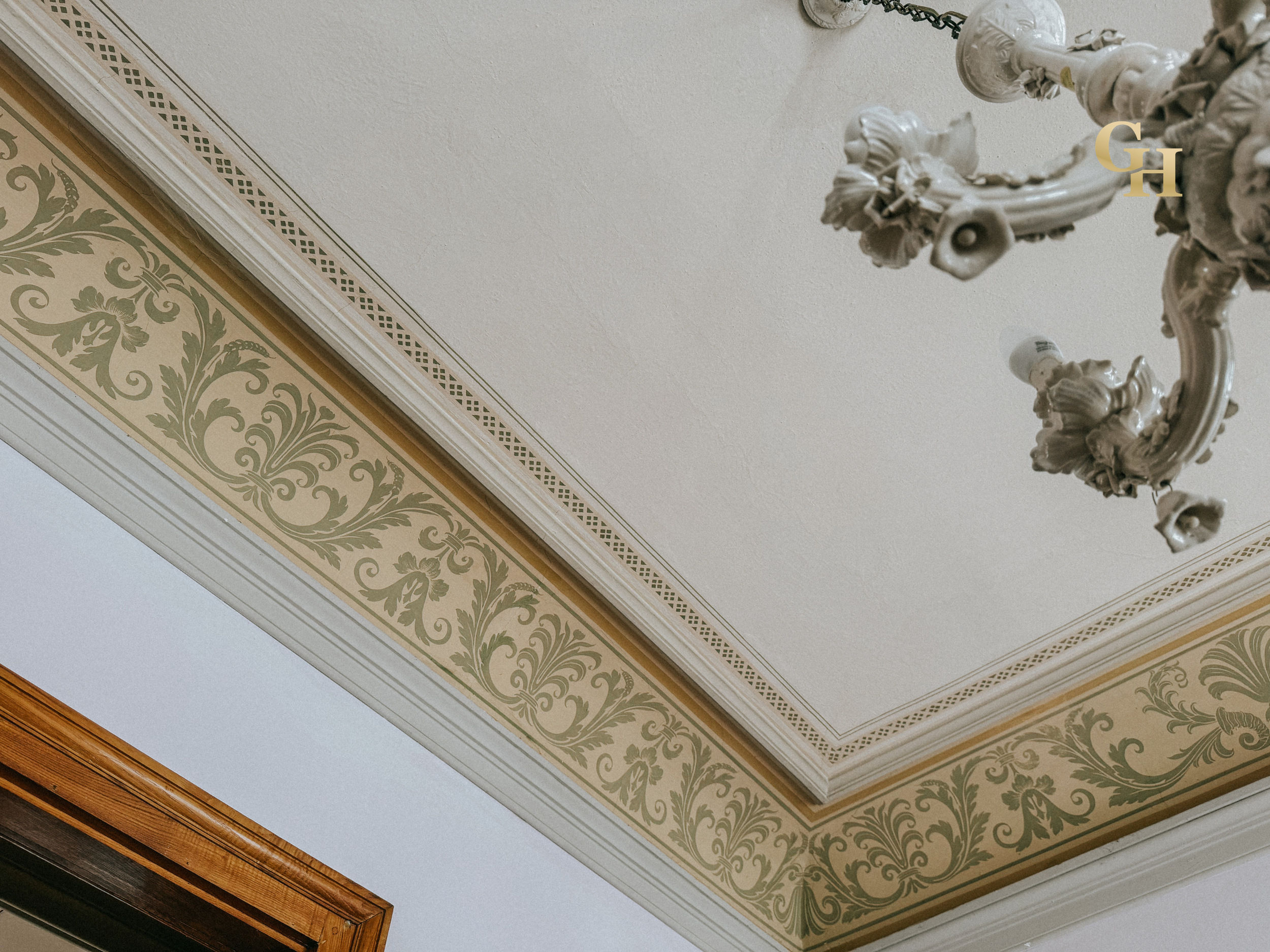 Ceiling with decorative molding, ornate chandelier, and a section of crown molding.