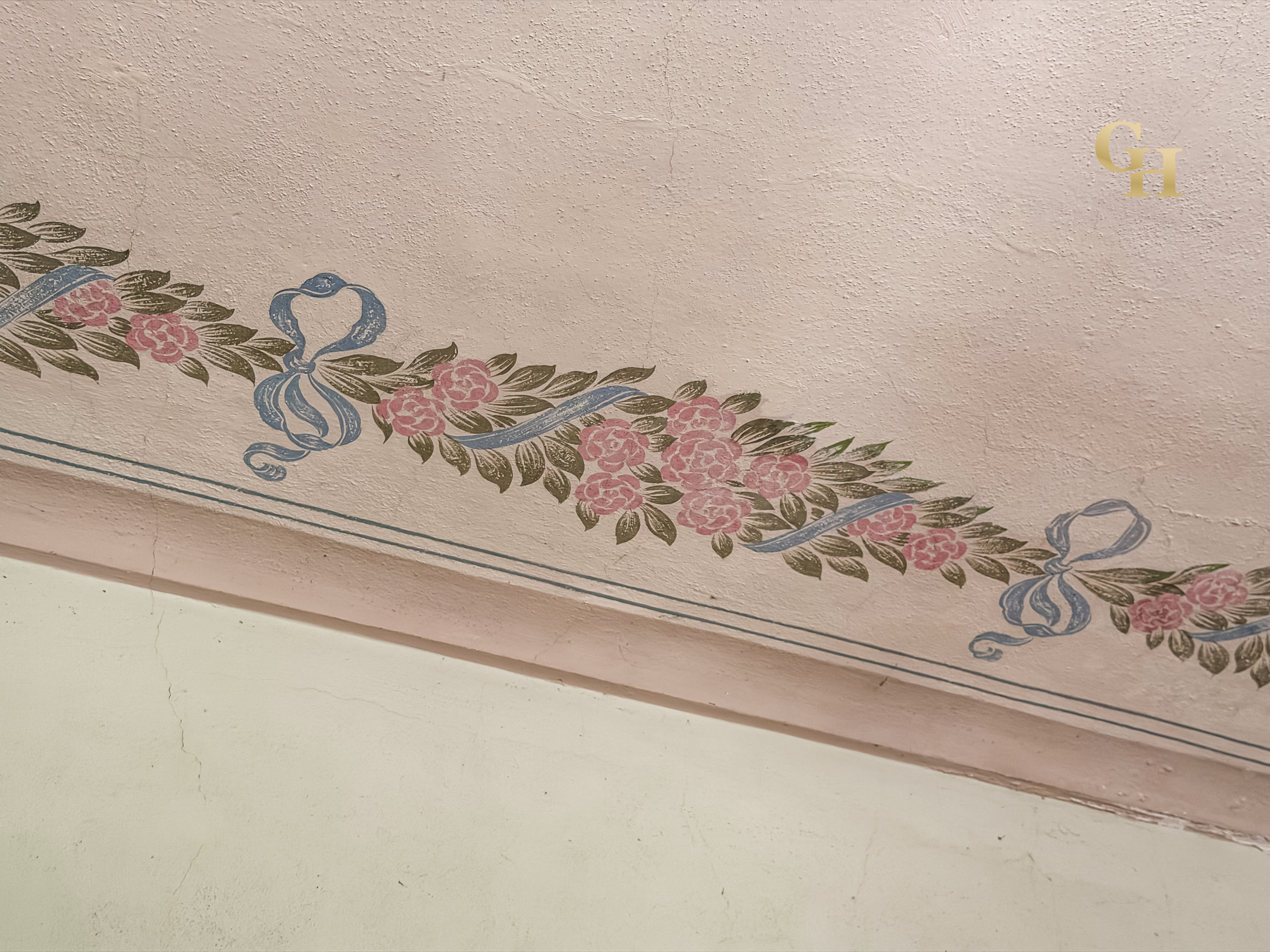 Decorative floral pattern with pink flowers, green leaves, and blue ribbons on a light pink textured ceiling or wall.
