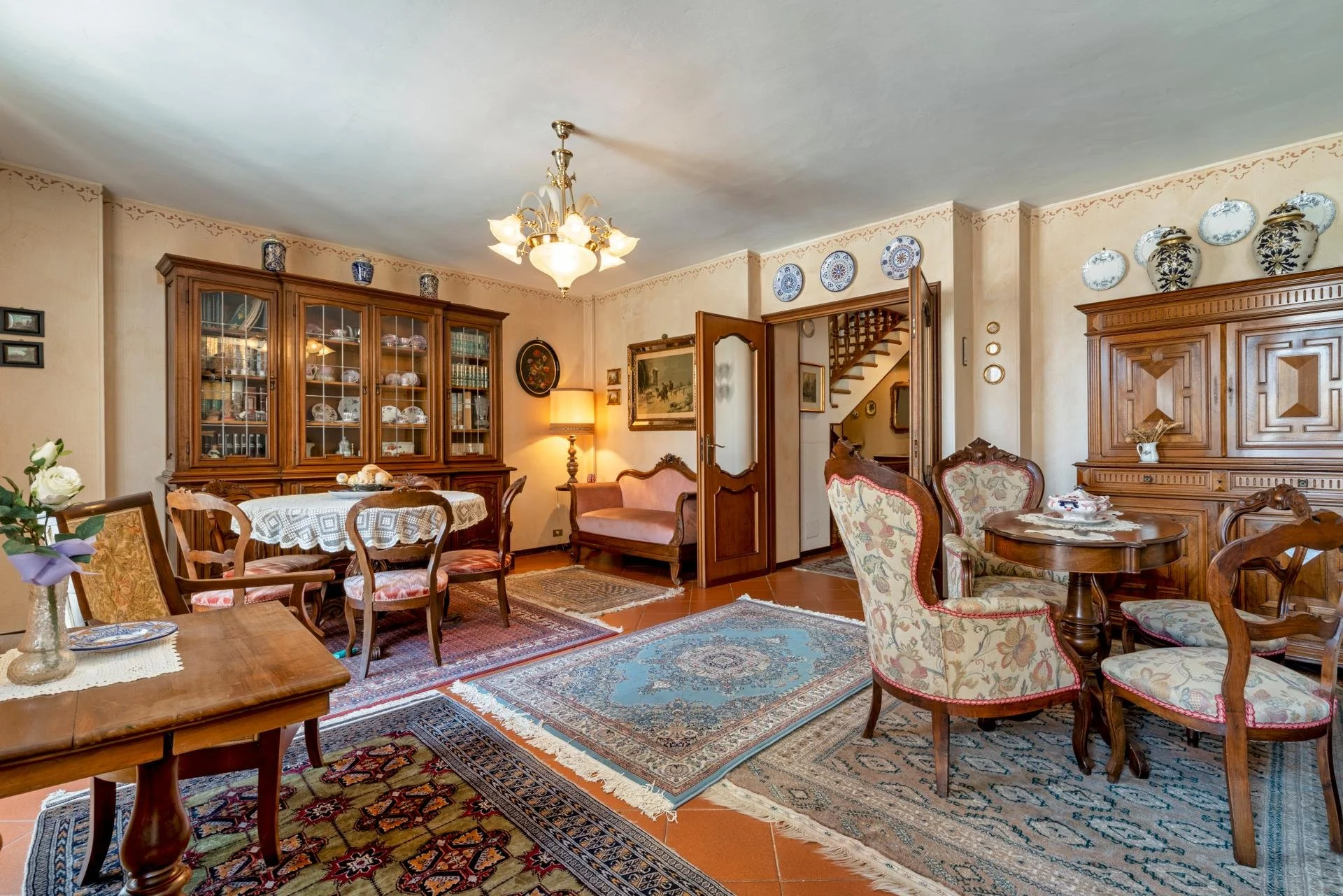 Living room with wooden furniture, patterned rugs, and decorative plates and vases on the walls and shelves.