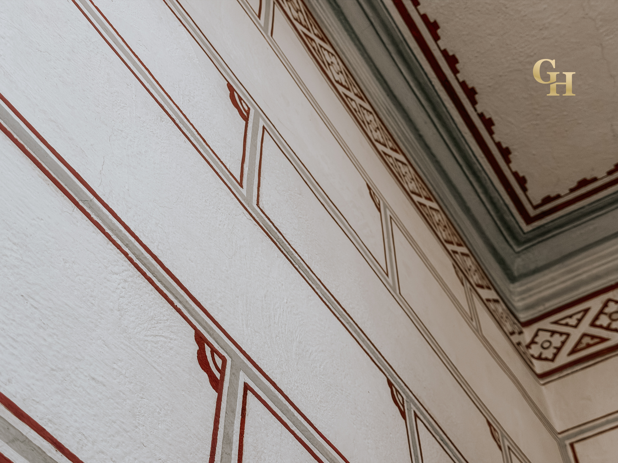 Close-up of a detailed, decorated wall or cuadro with a geometric pattern in red and beige colors, viewed at an angle.