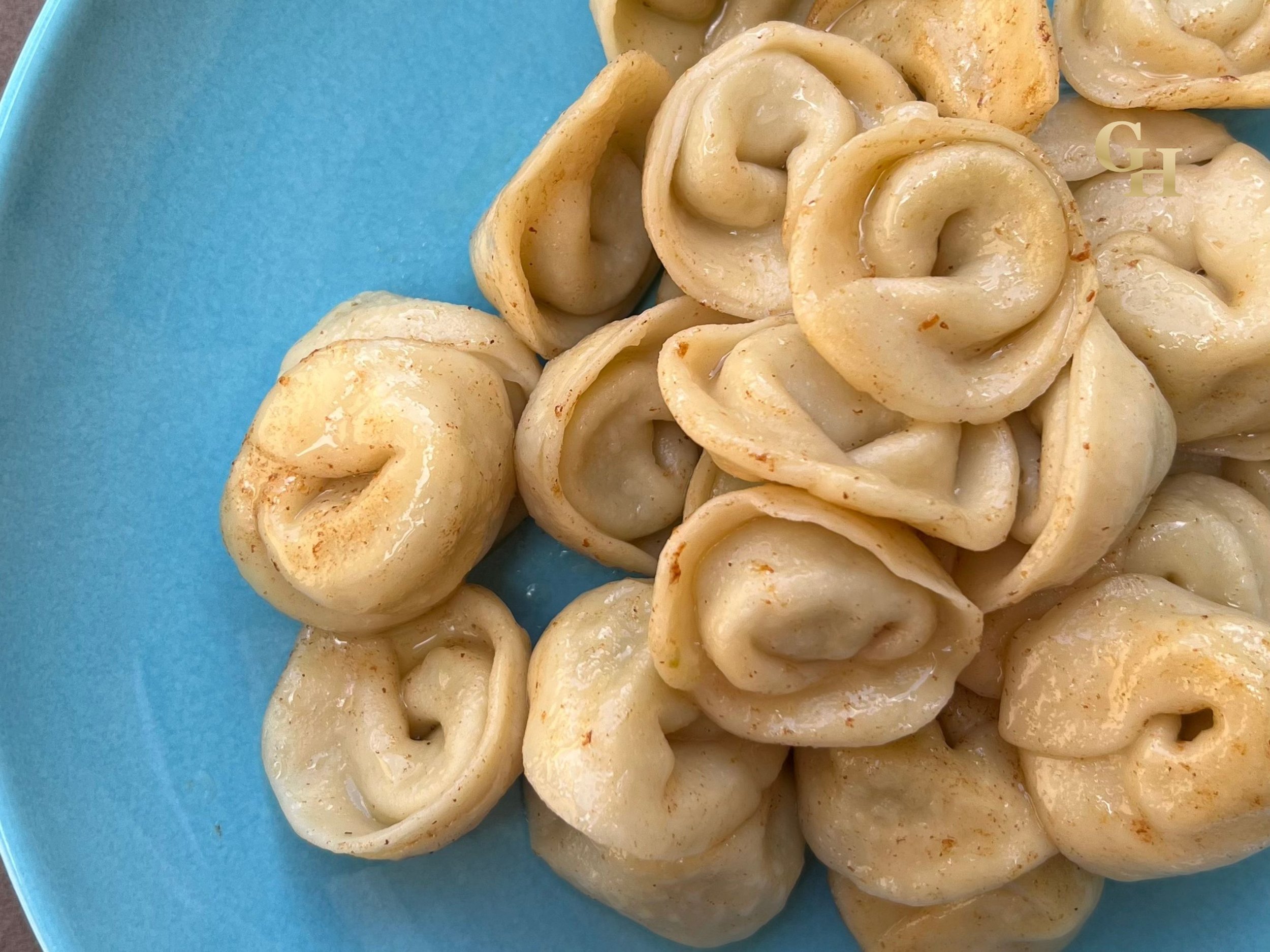 Fried tortellini pasta on a blue plate, garnished with spices.