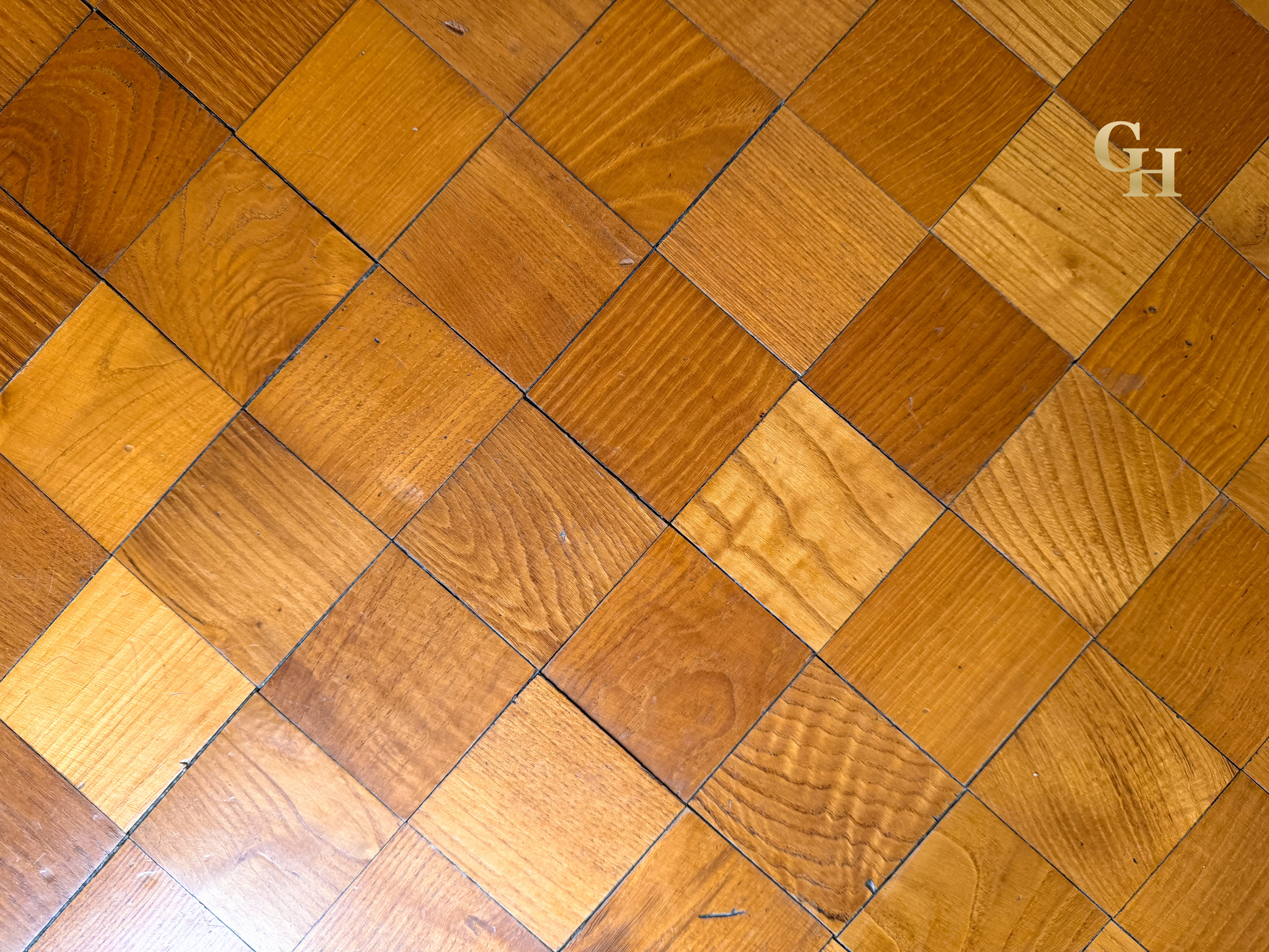 Close-up view of wooden floor tiles with a warm brown hue, arranged in a herringbone pattern.