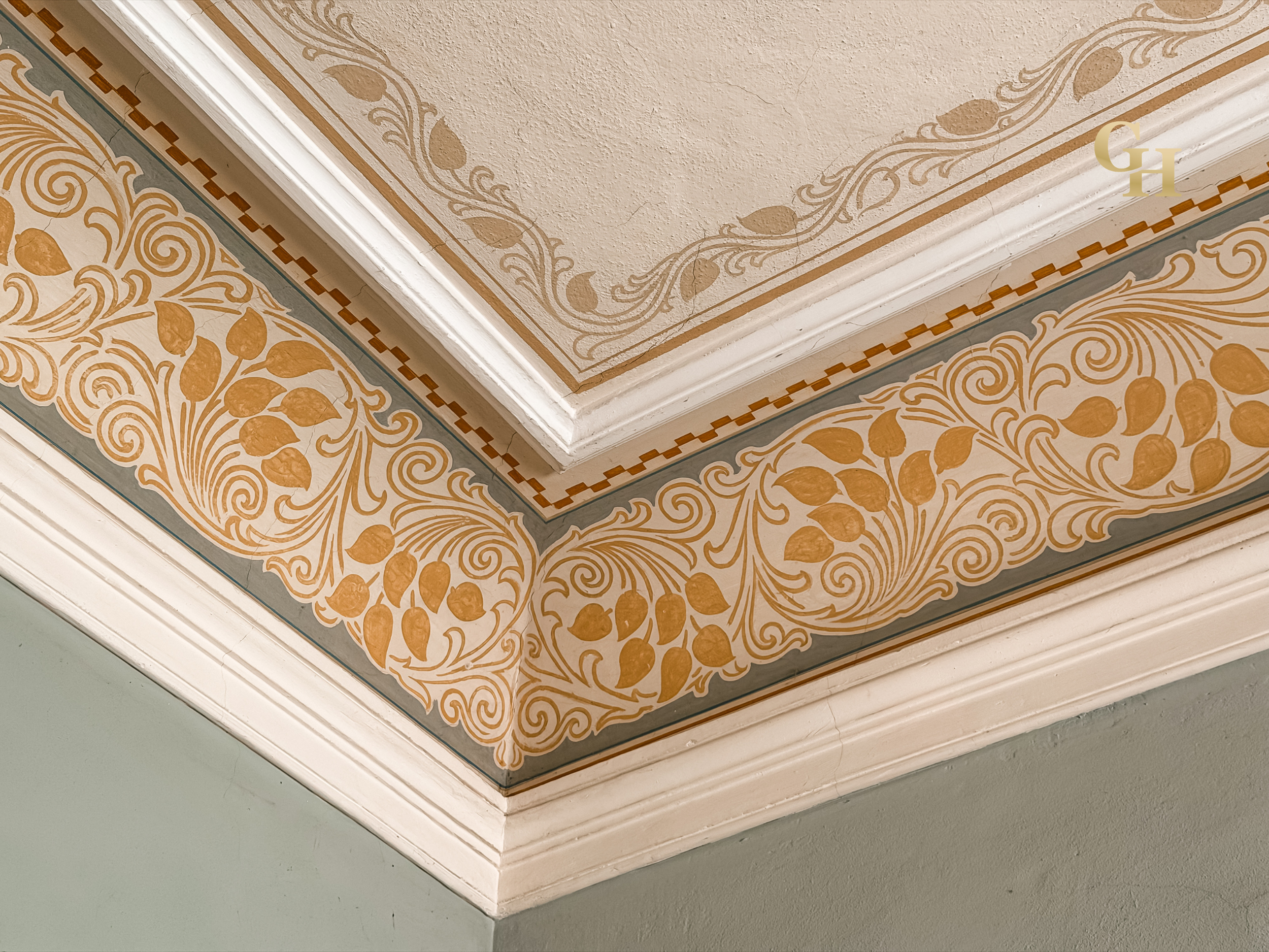 Decorative ceiling with intricate floral and scrollwork patterns in muted colors, white crown molding, and an ornate border.
