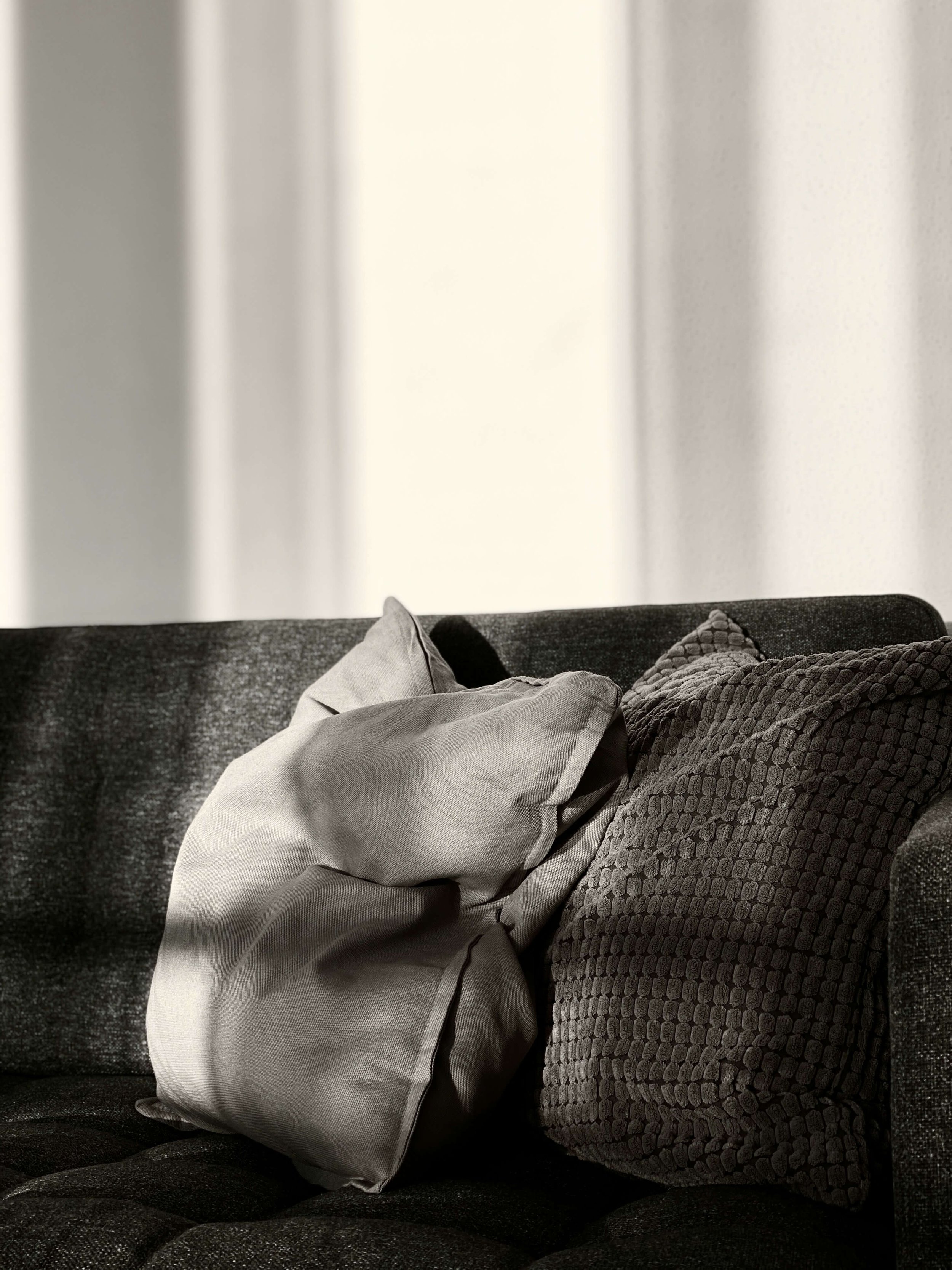 Close-up of neutral-colored throw pillows on a dark fabric sofa.