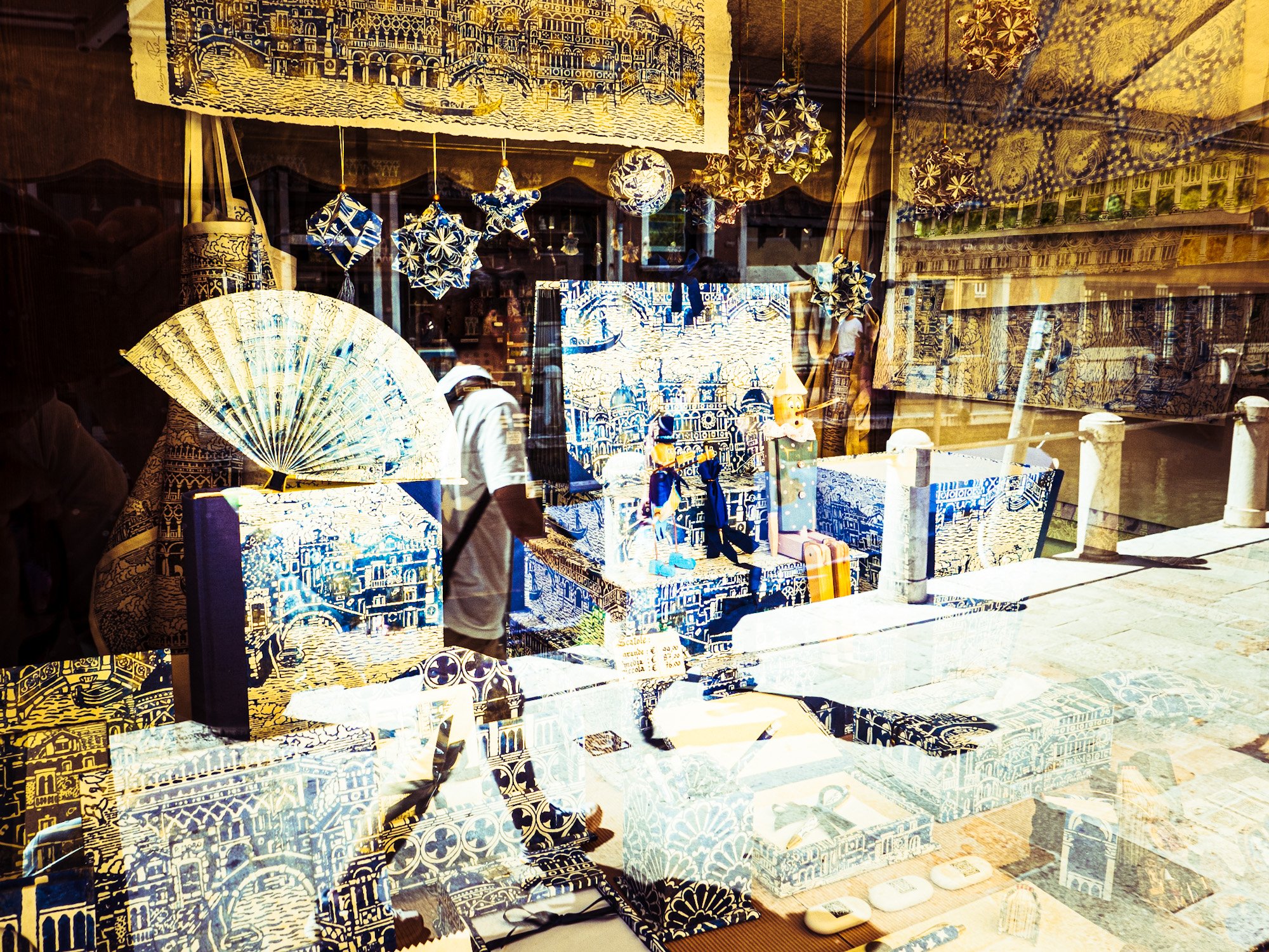 Schaufenster mit verschiedenen blauen und weißen handgefertigten Gegenständen, darunter Papierfächer, Sterne, Kugeln, Wandbilder und dekorative Stoffe, alle mit einem Istanbul-Motiv und aztekischen Mustern.