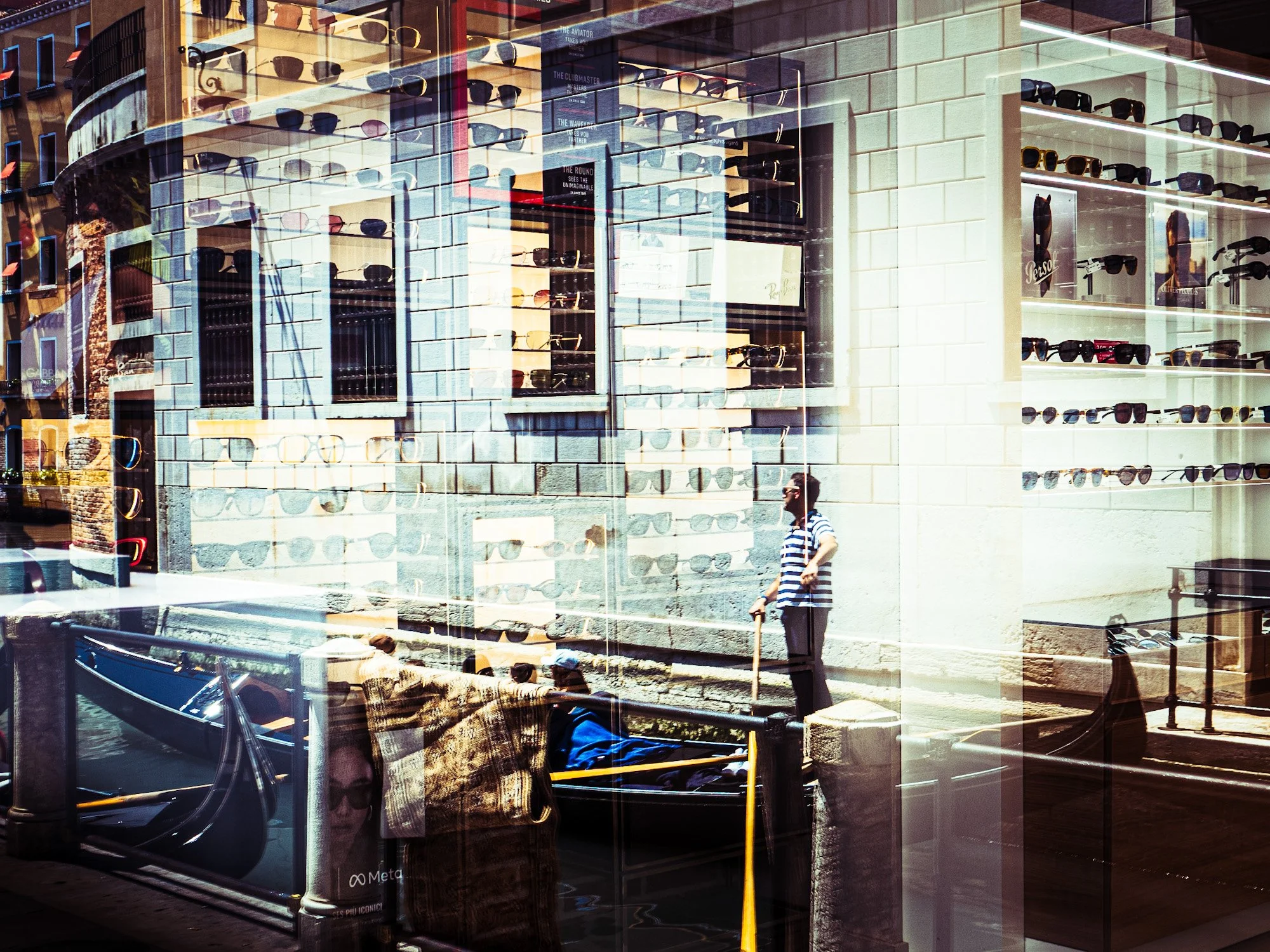 Schaufenster eines Optikergeschäfts mit Sonnenbrillen und Sonnenbrillenregalen, reflektierende Glasfassade, Stadtstraße mit Passanten, Straßenlaternen, Bauwerk im Hintergrund.