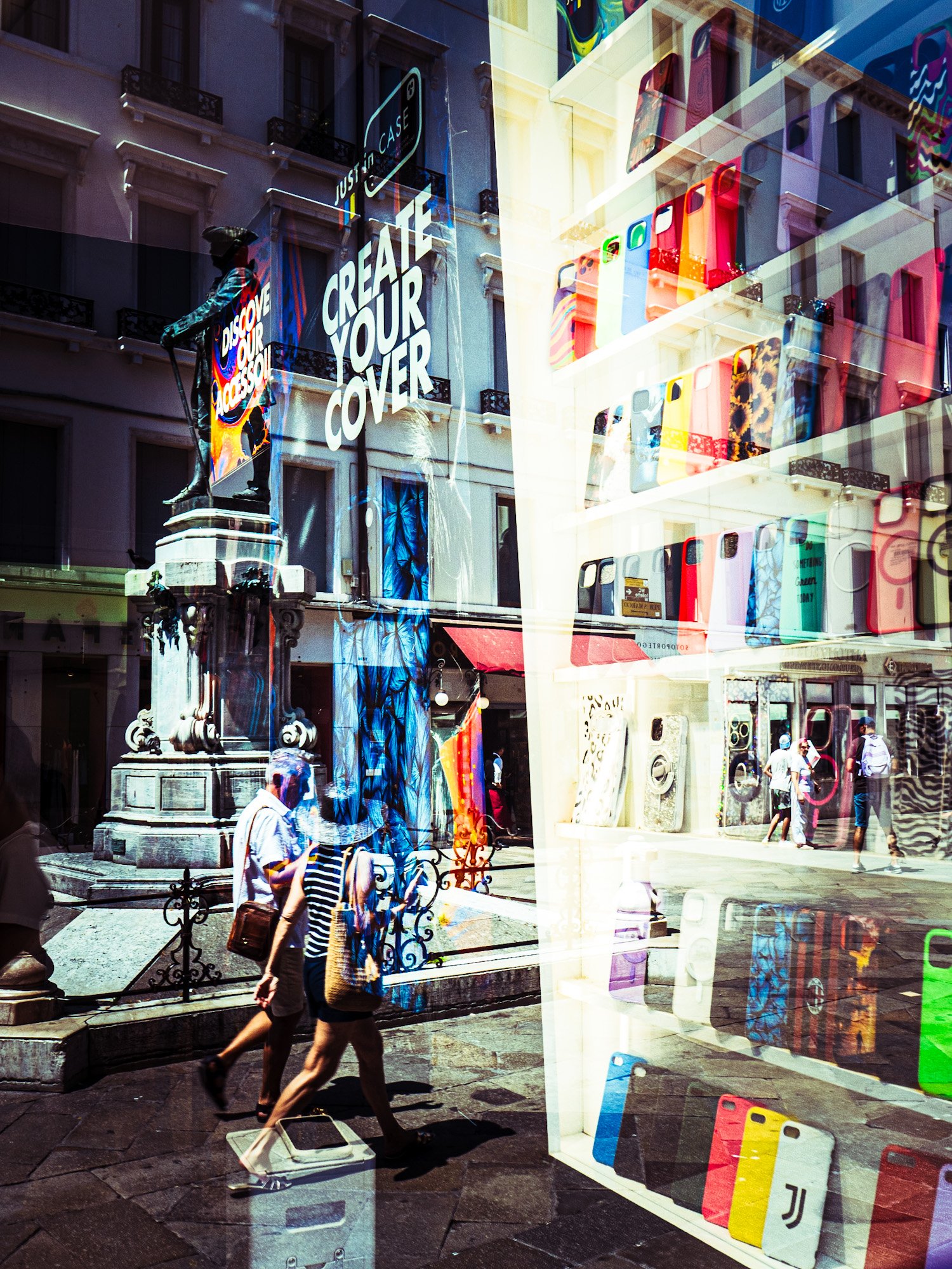 Stadtansicht mit Menschen, Geschäften und reflektierenden Schaufenstern, die bunte Handyhüllen und einen Schriftzug „Create Your Cover“ anzeigen.
