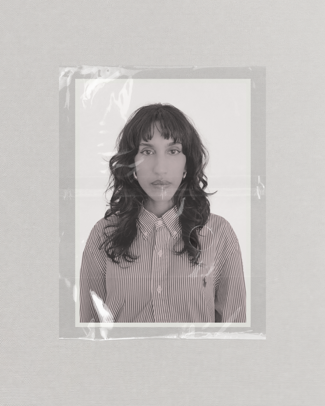 Front-facing portrait of fashion designer Daniela Vargas wearing a striped shirt under plastic film
