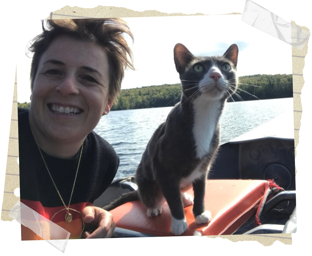 Winter Miller smiling on a boat with her cat, both looking outdoors over a lake with greenery in the background.
