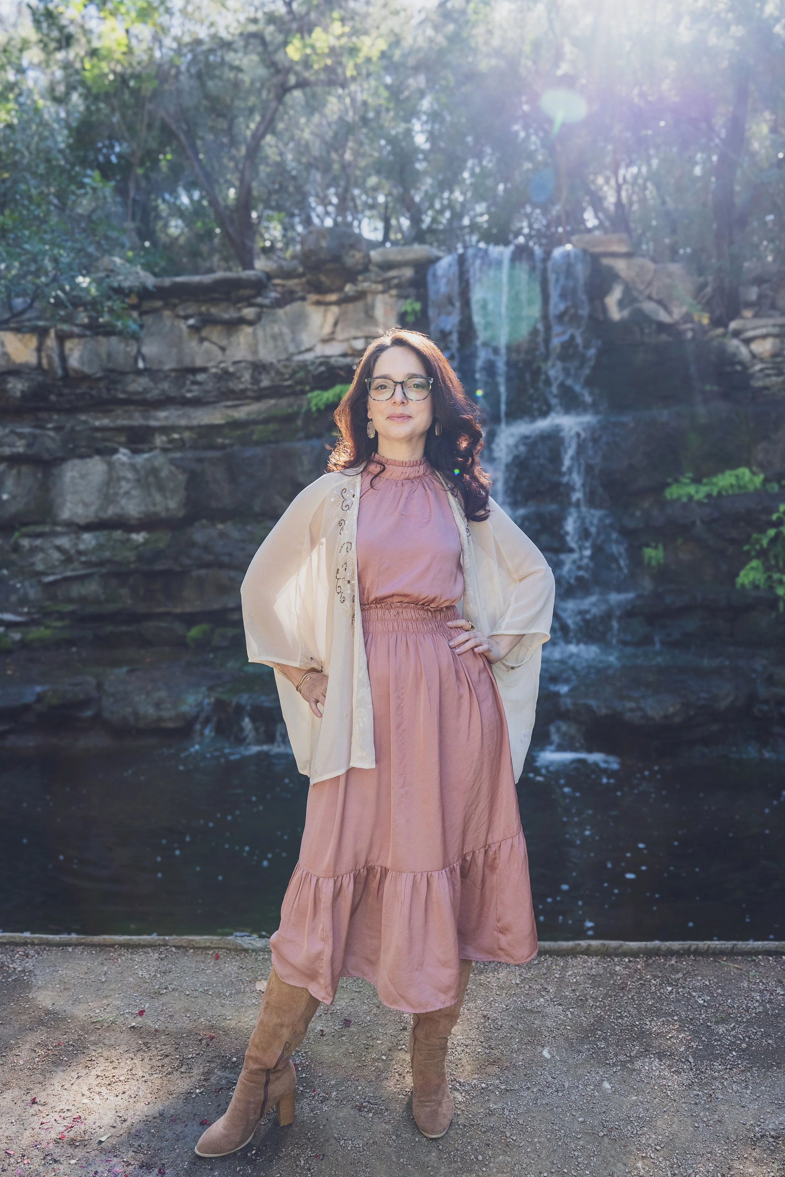 Dr. Jane stands confidently in front of a waterfall.