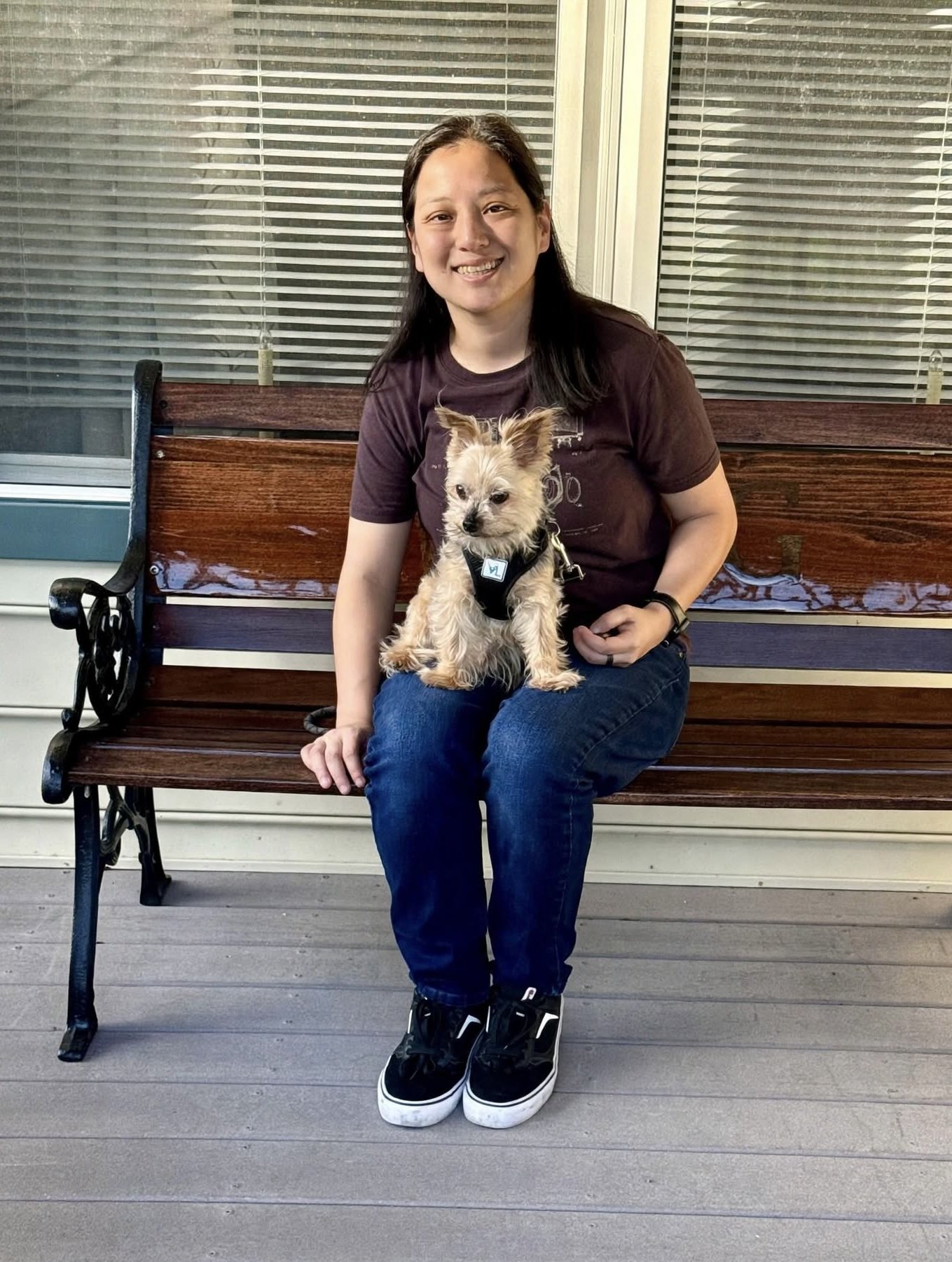 Elizabeth, founder of Lucky's Watch Pet Services, sitting on a porch bench with her dog Sloan on her lap.