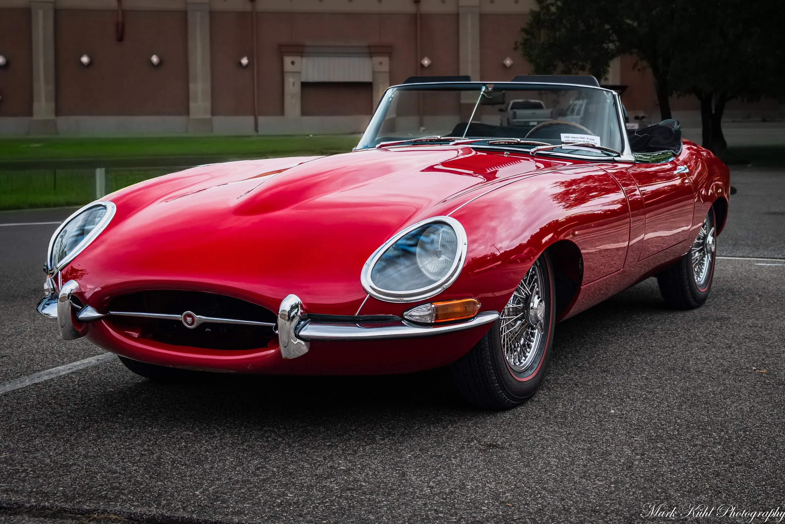A red vintage 1966 Jaguar XKE convertible parked outside during the daytime.