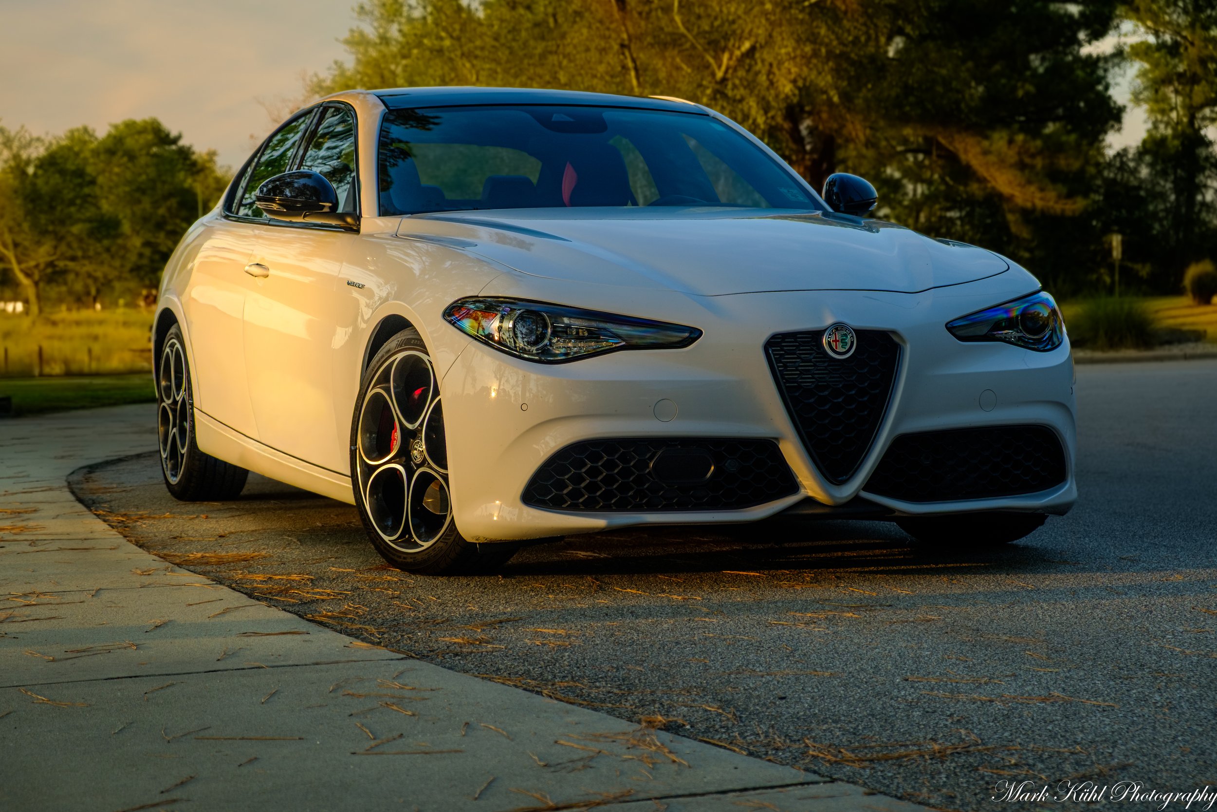 A white Alfa Romeo sports car during a sunset photo shoot.