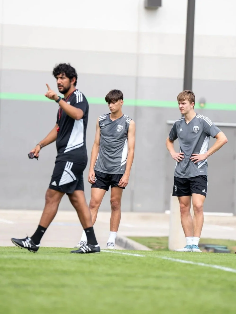 Soccer coach giving instructions to young players on the field in training.