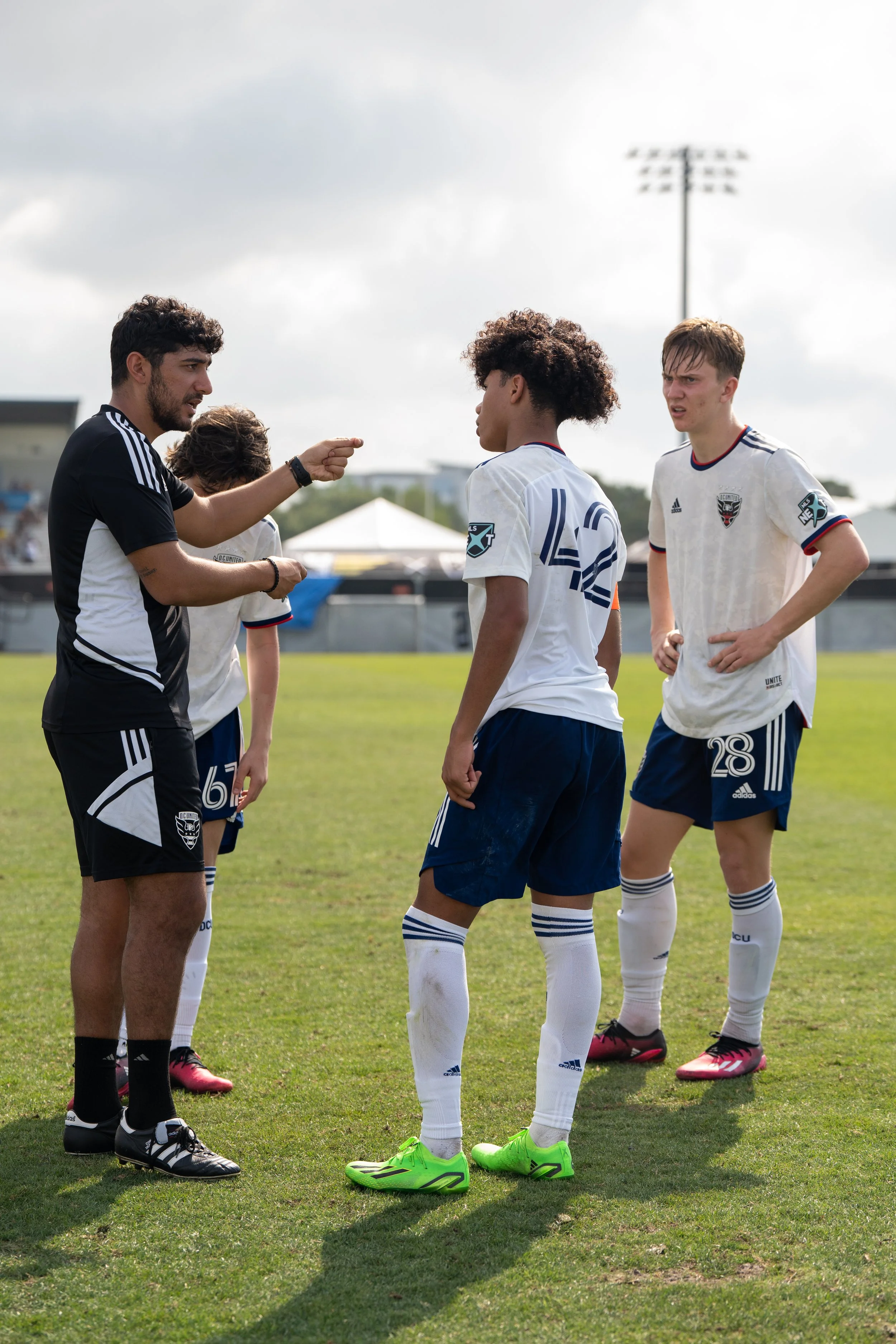 Soccer coach giving instructions to young players on the field during a game.