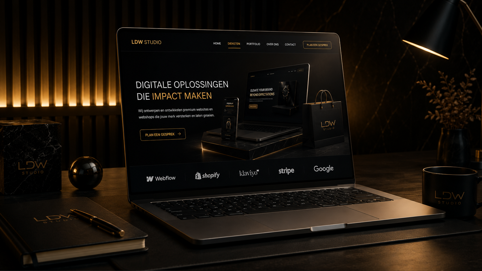 Een laptopscherm toont een website voor LDW Studio, met de titel 'Digitale oplossingen die impact maken' en knop 'Plan een gesprek'. Op de tafel staan een notitieboekje met pen, een mok en een doos en bal van black marble met goudkleurige teksten, alle met het LDW Studio logo. De achtergrond heeft warm verlichte verticale houten panelen.