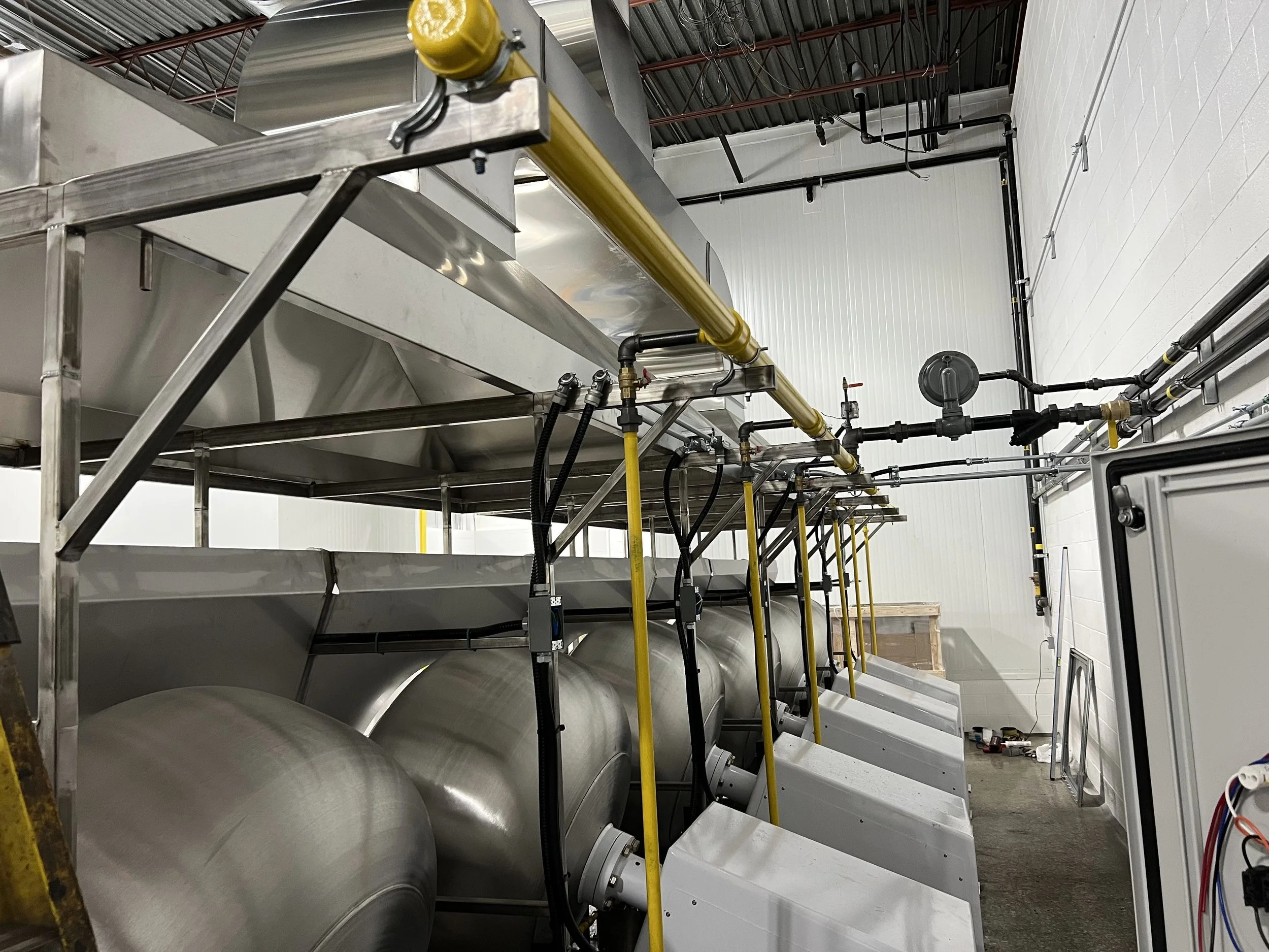 Industrial stainless steel equipment with pipes and gauges in a factory or processing plant.