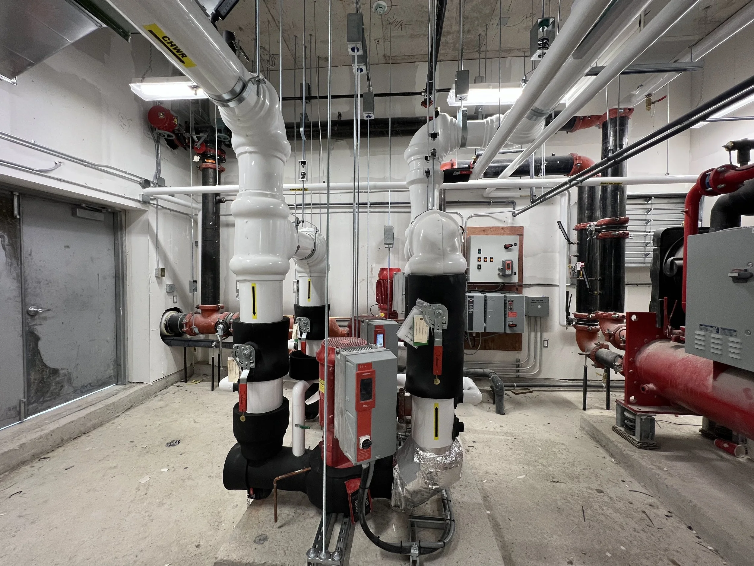A mechanical room with pipes, pumps, and valves.