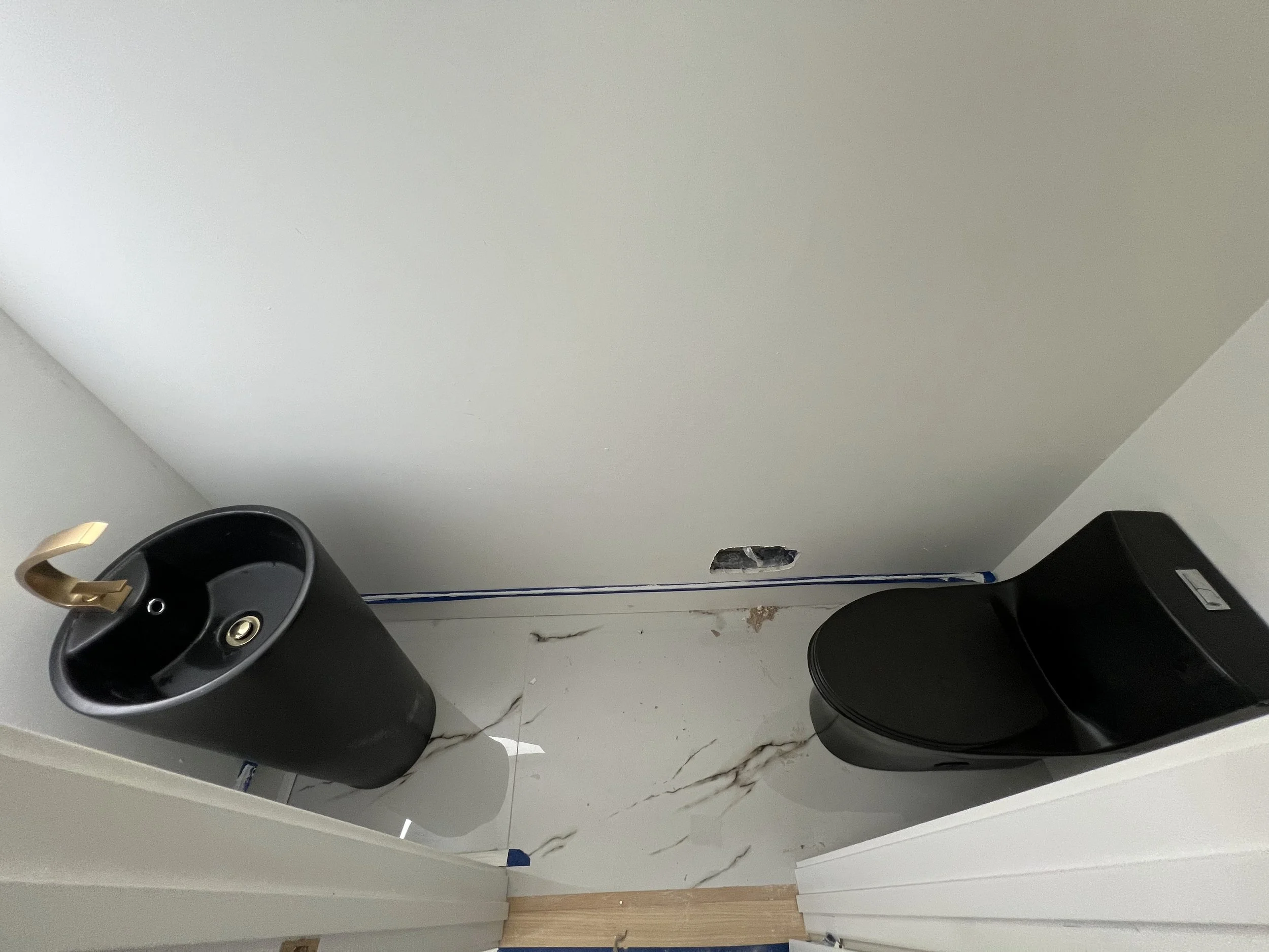 Broken ceiling with a hole, two black speakers, a gold-colored clip, and construction debris on the floor.