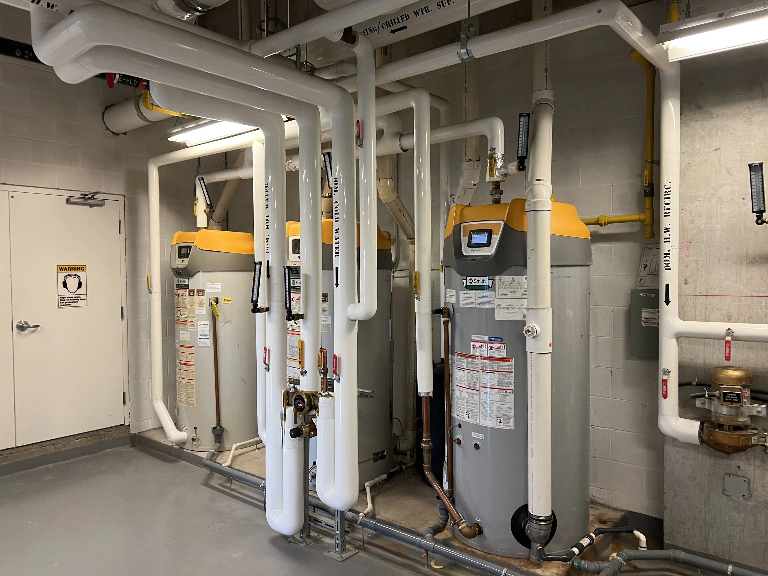 Plumbing system with large pipes, valves, and industrial equipment in a utility room.