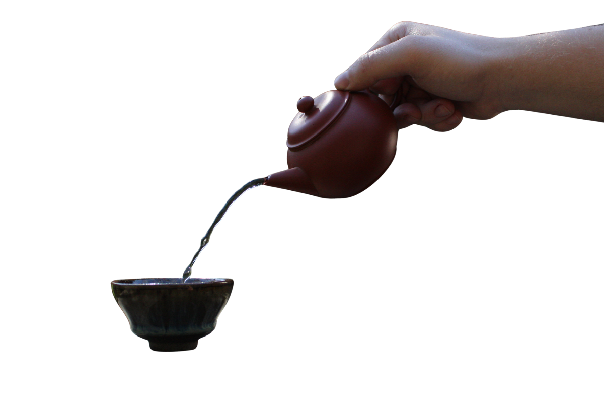 Person pouring tea from a small brown teapot into a bowl.