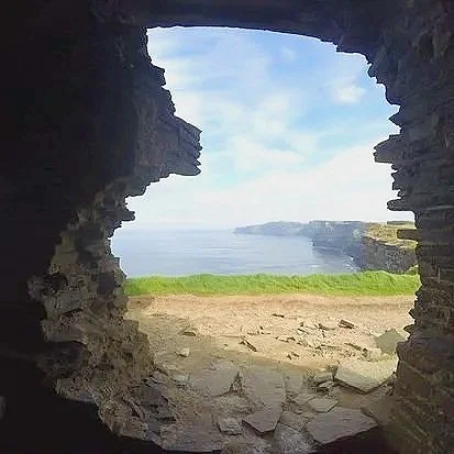 View of the ocean and coastline through a holes in a stone or brick structure