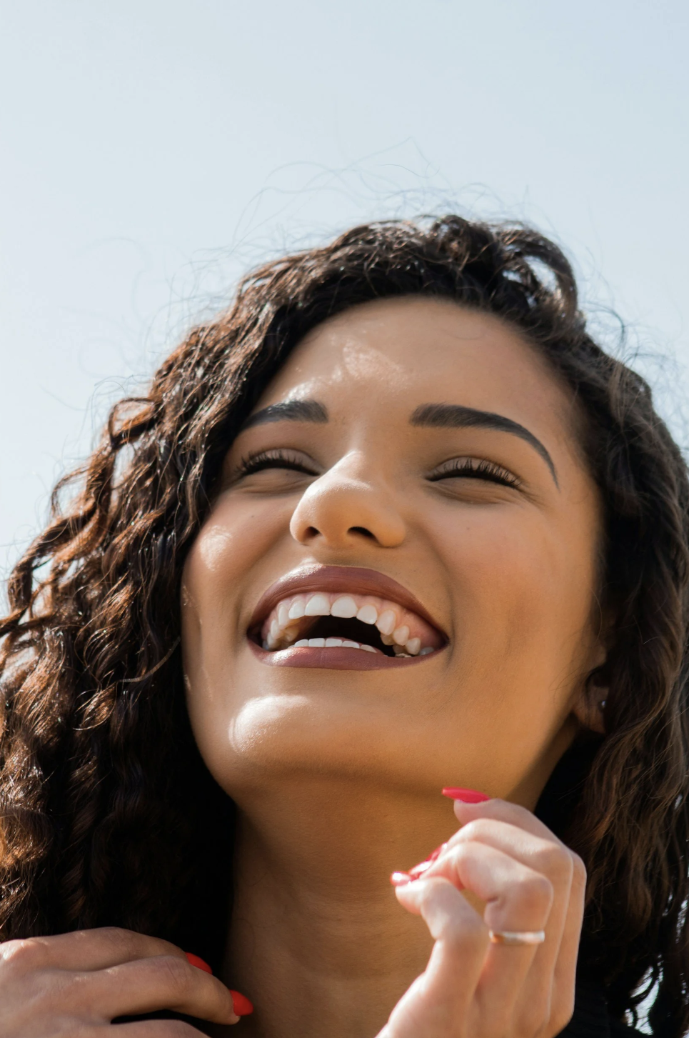Confident woman laughing and looking up, representing the freedom and breakthroughs entrepreneurs experience after releasing inner blocks with TOPT coaching