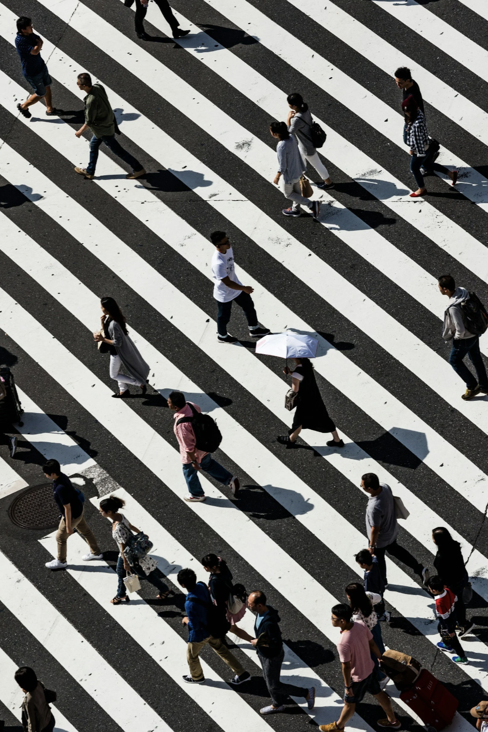 Aerial view of people walking freely across a crosswalk representing clarity focus and forward momentum entrepreneurs gain after breaking through subconscious patterns and inner blocks