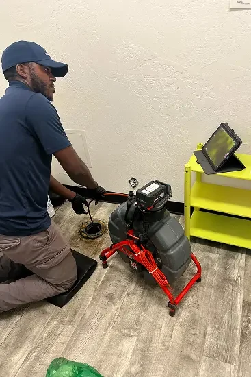Your Drain Guy, working with equipment connected to a drain scanning for obstructions with a camera on a yellow table nearby.