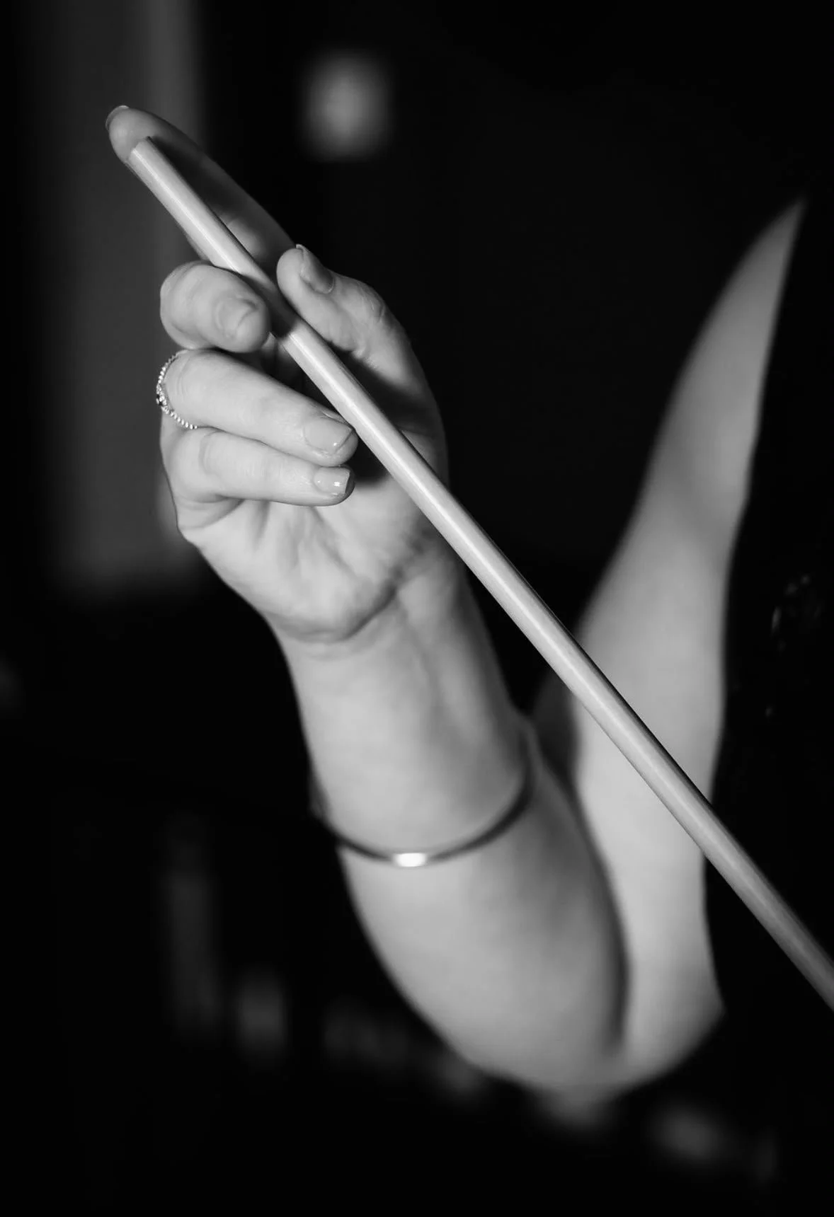A person holding a cane in their left hand, with their fingers partially visible. The person has a bracelet on their wrist and a ring on their finger. The photo is in black and white.