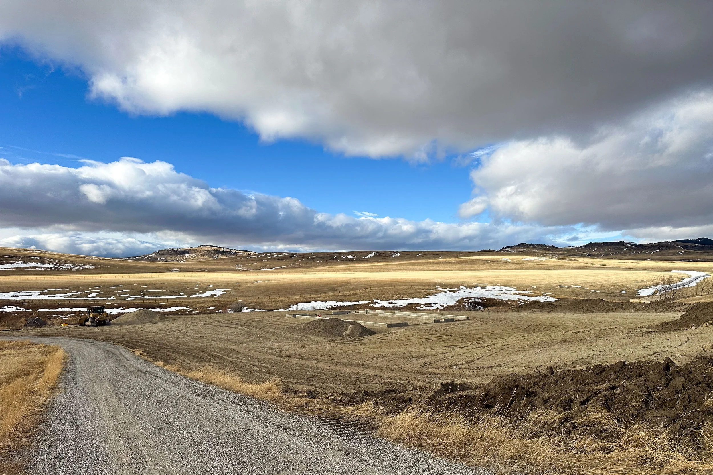A rural Alberta landscape with a excavated landscape around a freshly-poured foundation.