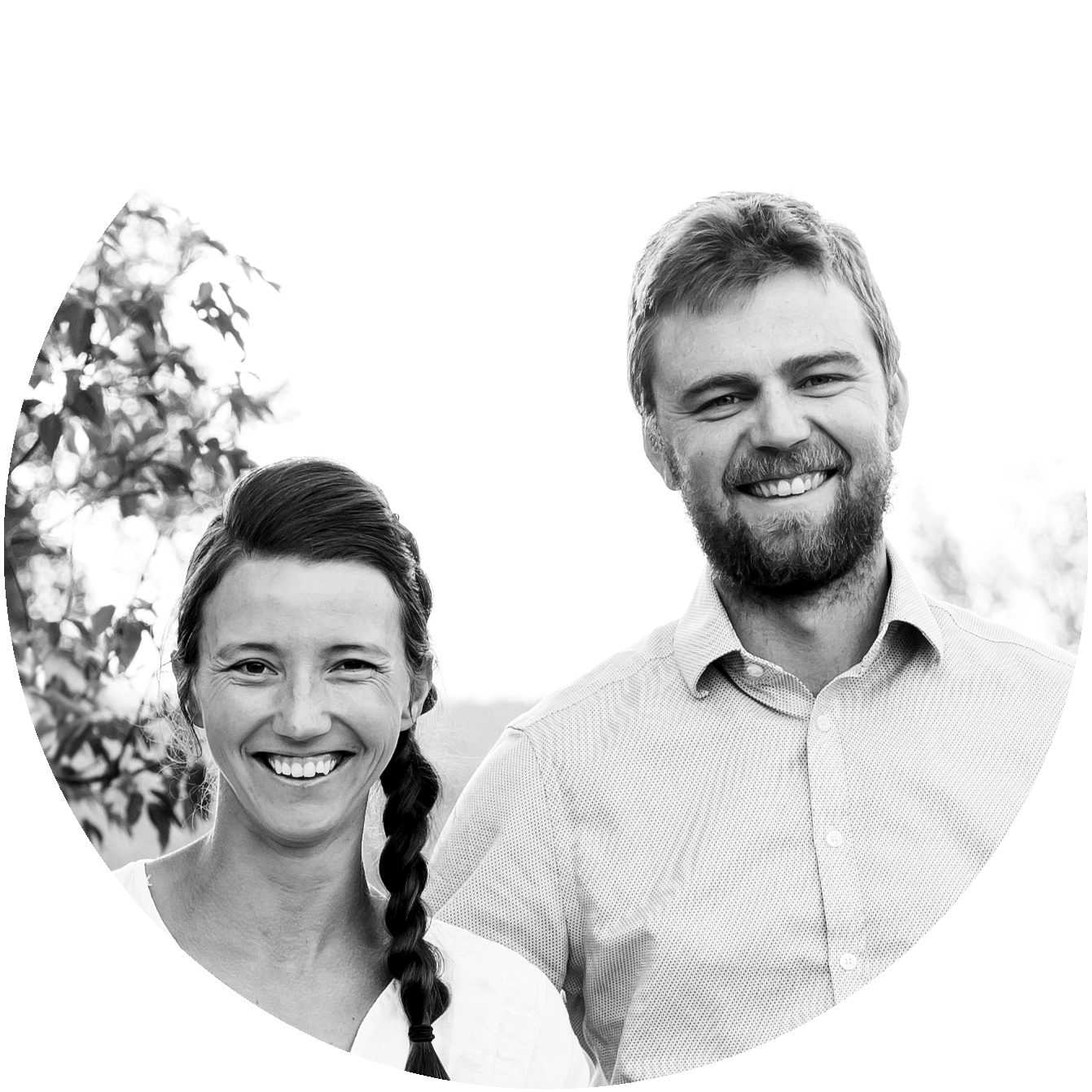 Black and white photo of a smiling man and woman outdoors, with trees in the background.