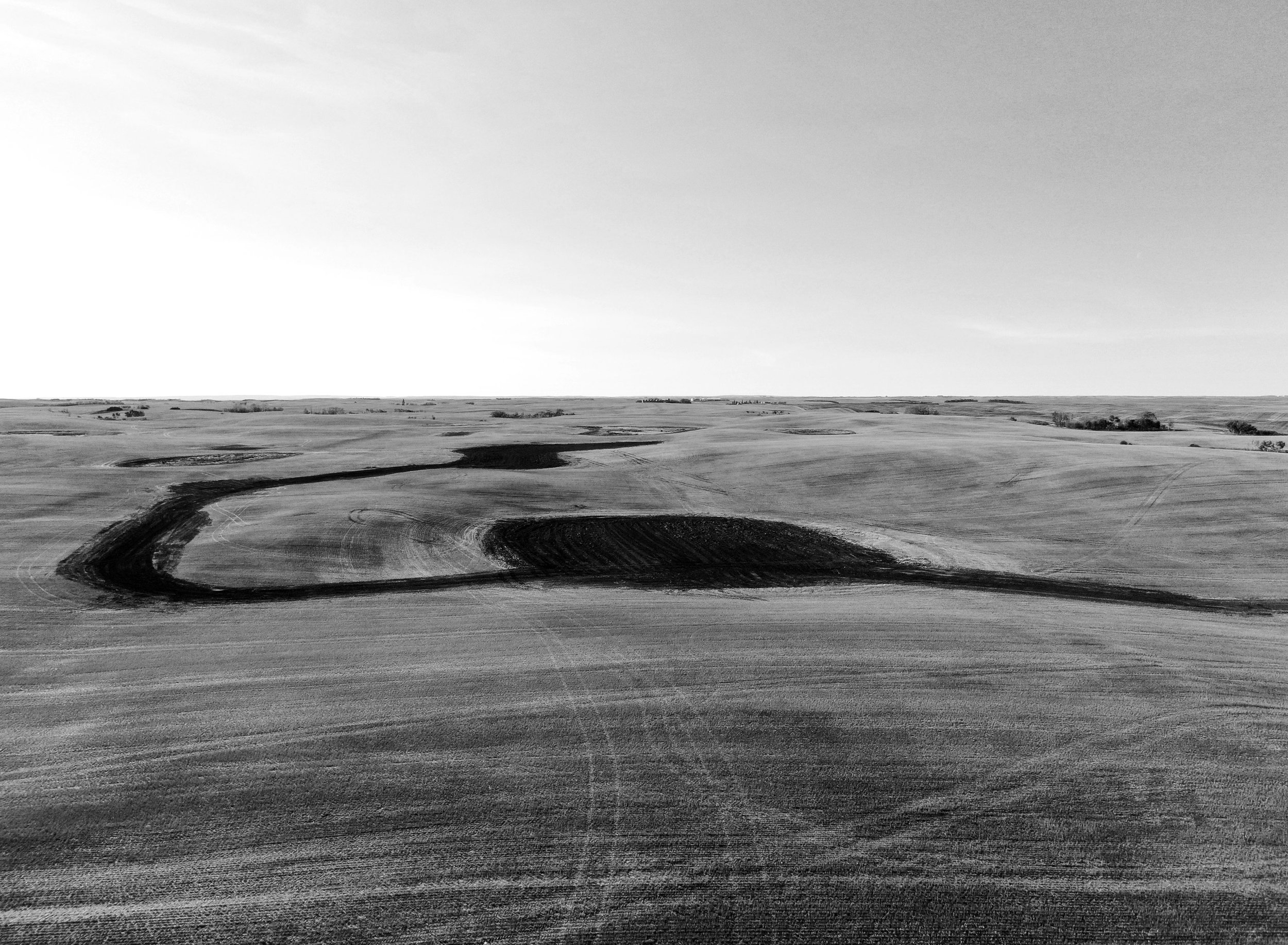 A black and white photograph of an expansive landscape with strategic land drainage excavation.