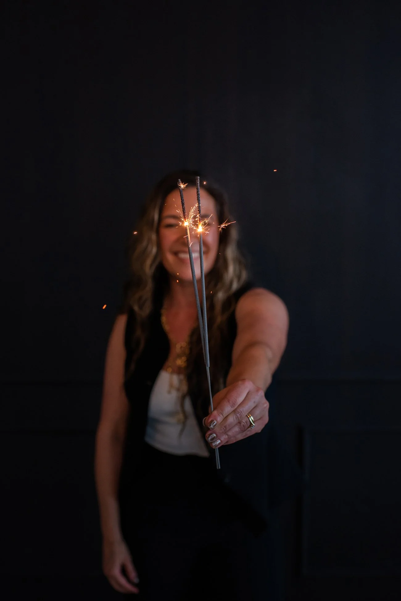 Chantal Menard holding sparklers in front of a dark background, smiling at the camera.