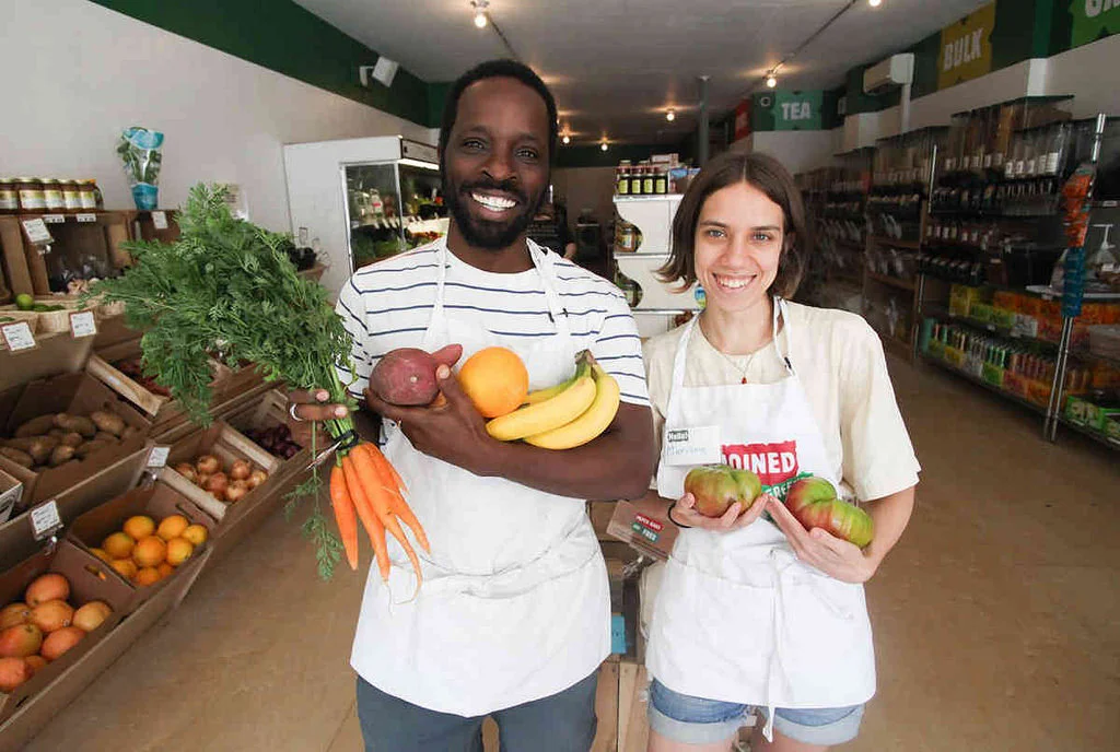 Co-op member-owners Calixte and Mariana show off fresh produce. Photo courtesy of Brooklyn Paper.