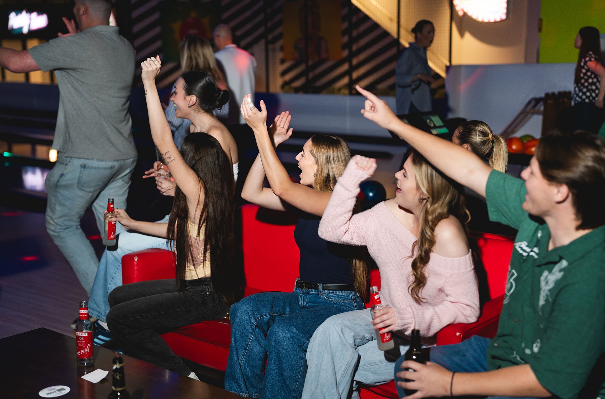 Group of young adults enjoying drinks and dancing at a bar or nightclub.