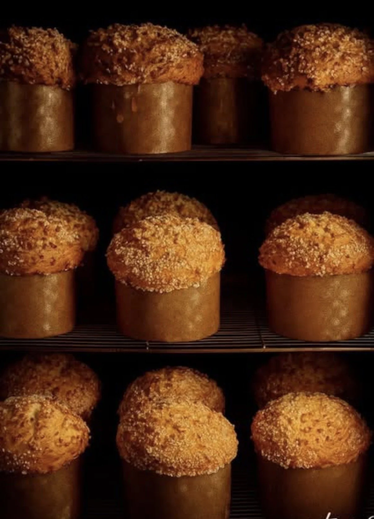 Gâteaux de pâte à choux fourrés, recouverts de sucre ou d'amandes, dans des moules en forme de cylindre, en train de cuire au four.