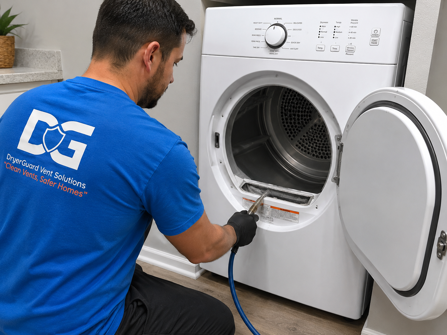 A technician cleaning the inside of a front-loading washing machine using a spray tool. The technician is wearing a blue shirt with the logo 'DGS' and the text 'DryerGuard Vent Solutions' along with the slogan 'Clean Vents, Safer Homes'.