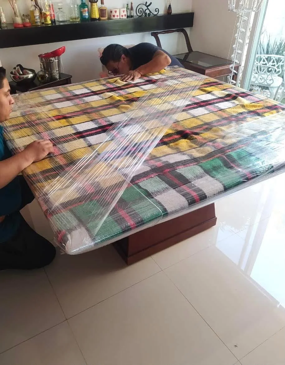 Personal de fletes y mudanzas protegiendo una mesa  delicada con playo y manta 