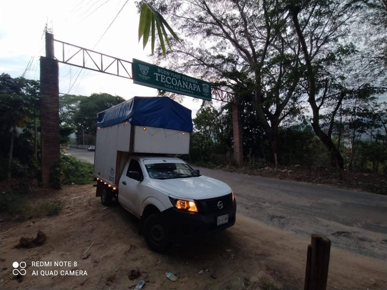 Camioneta blanca estacionada sobre la carretera, con cartel que dice 'Buen viaje, te desea Tecpanapa'. Despues d entregar un servicio con exito