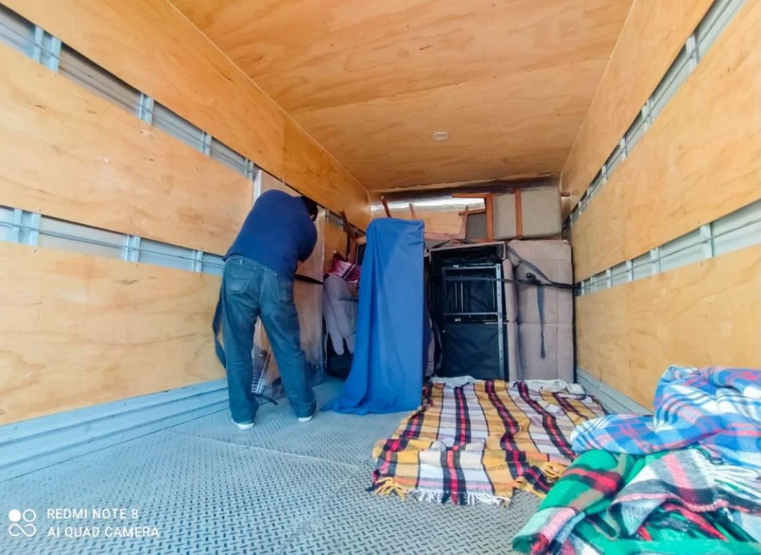 Personal cargando mobiliario en una caja de camion,protegiendo el mobiliario con mantas