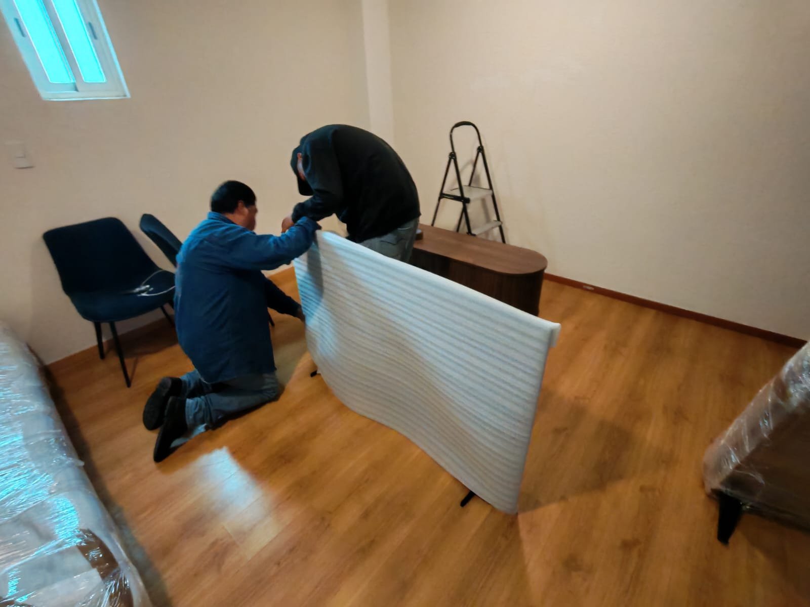 Personal realizando una maniobra de embalaje con material como bajo alfombra y plastico polystrech 