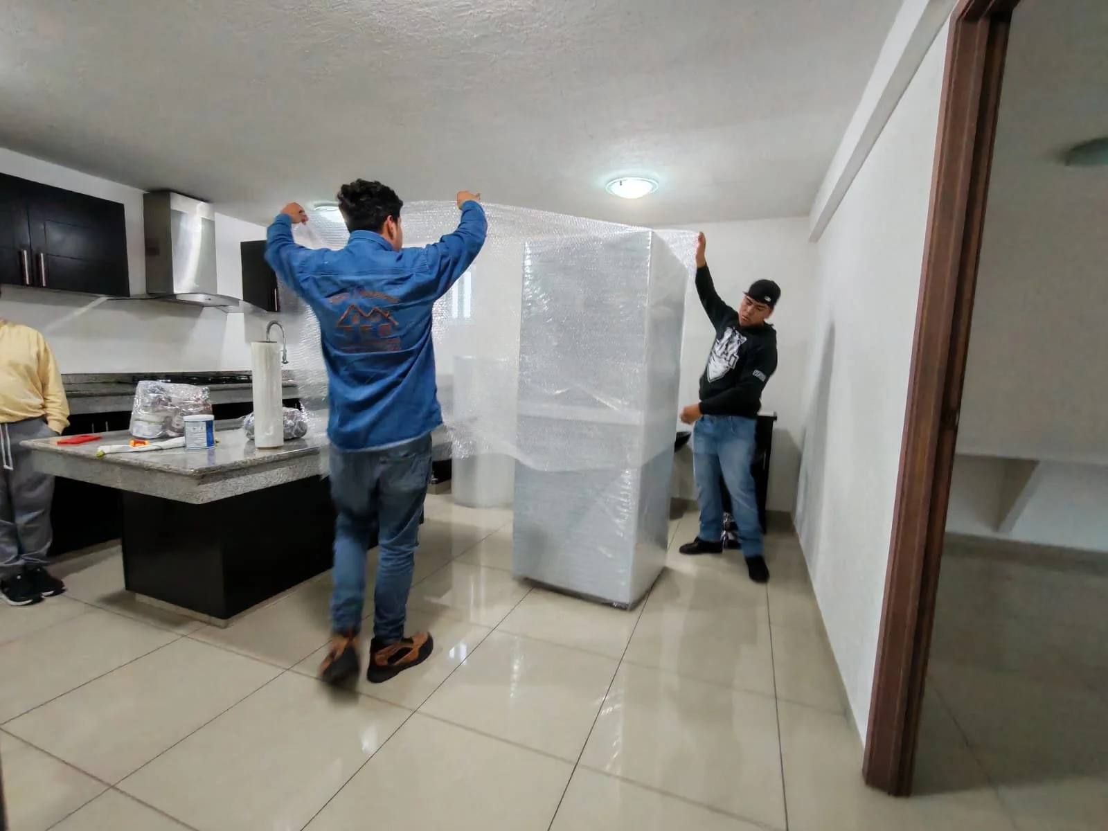 Dos maniobristas protegiendo el mobiliario con material de empaque como plástico de burbujas para una mudanza segura