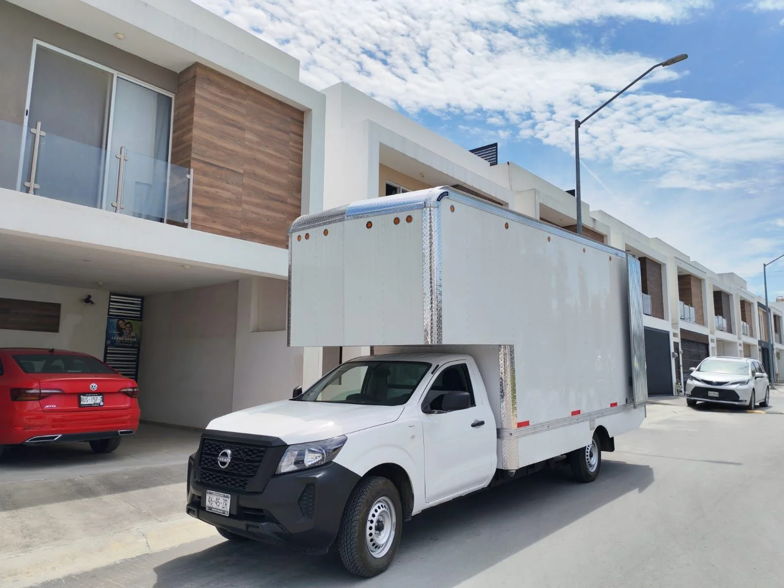 Camioneta blanca frente a un residencial terminando de entregar un servicio con exito