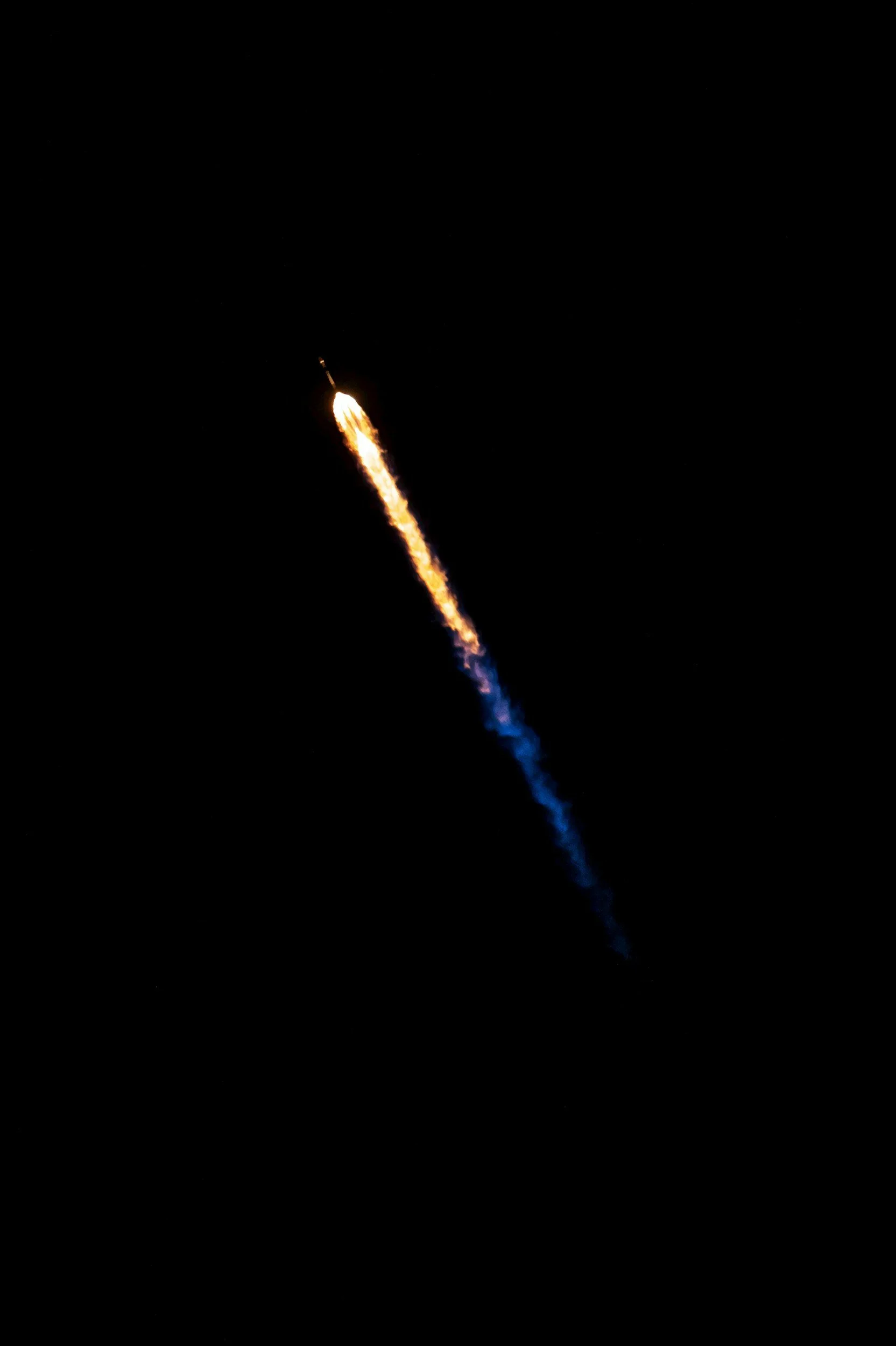 A rocket launching into the night sky, with a bright flame and smoke trailing behind it.
