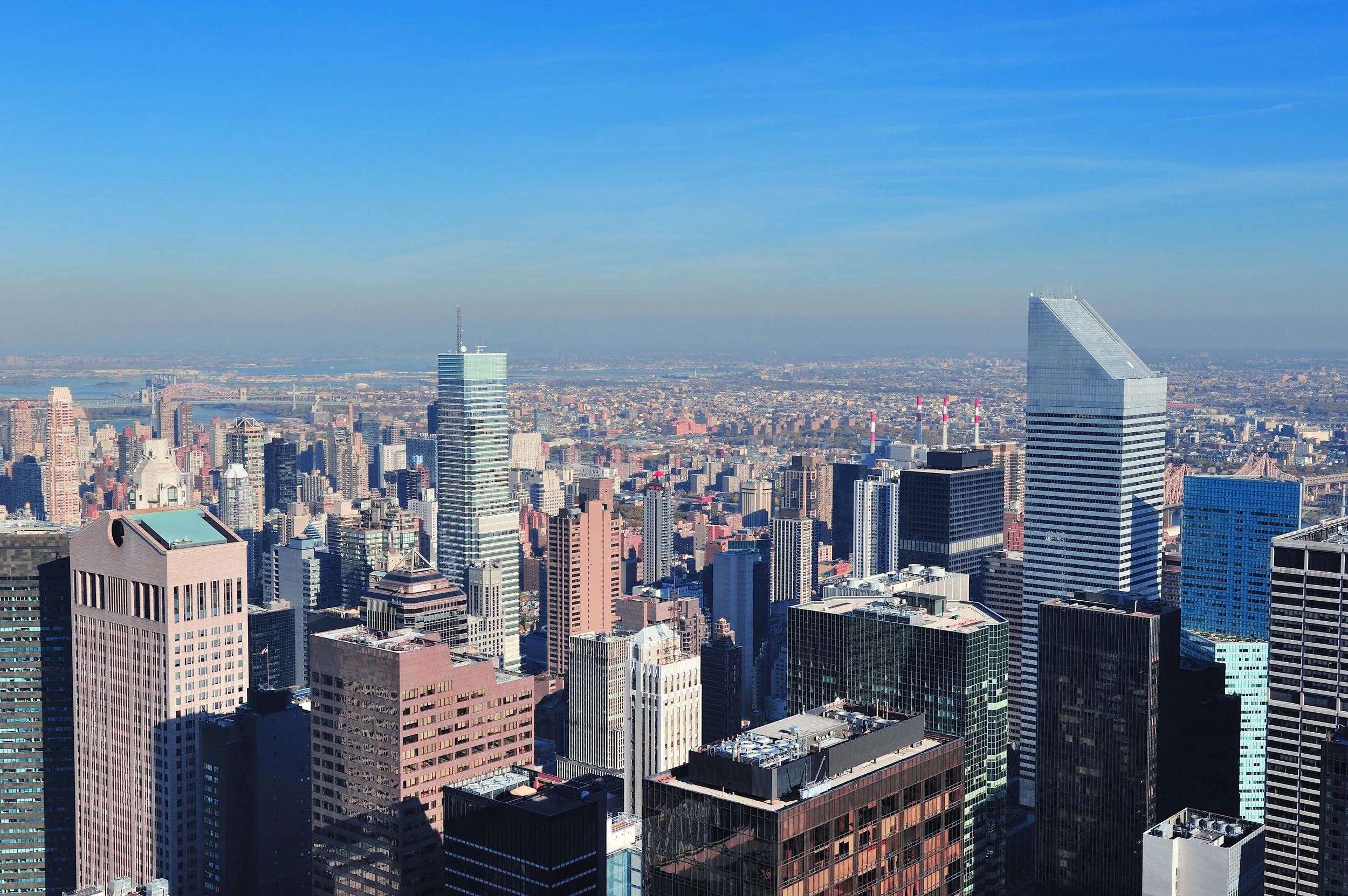 A city skyline with numerous tall skyscrapers under a clear blue sky.
